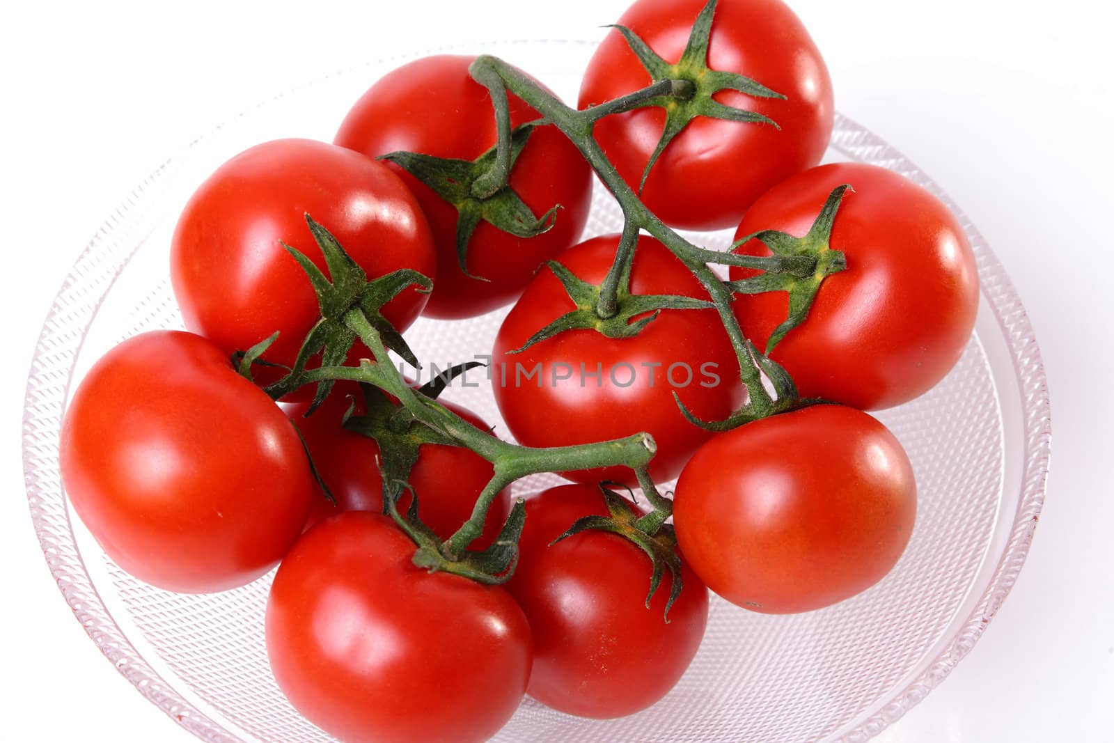 Red tomatoes in a glass cup on white background