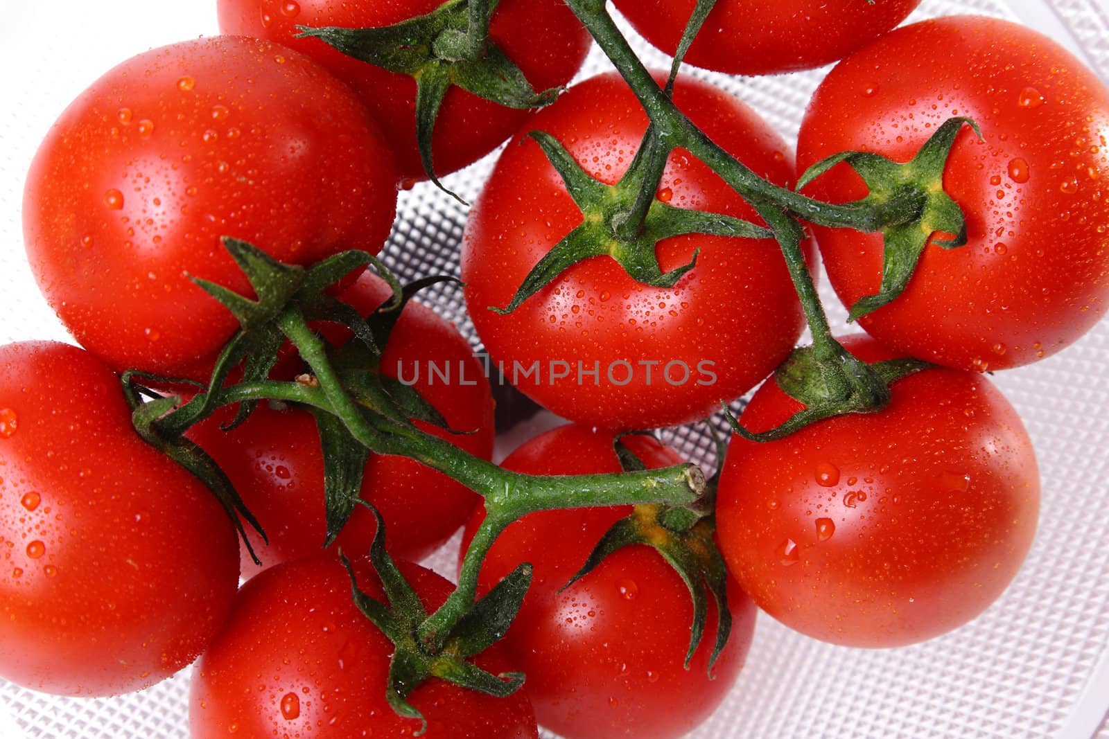 Glass basket with red tomatoes and water drops