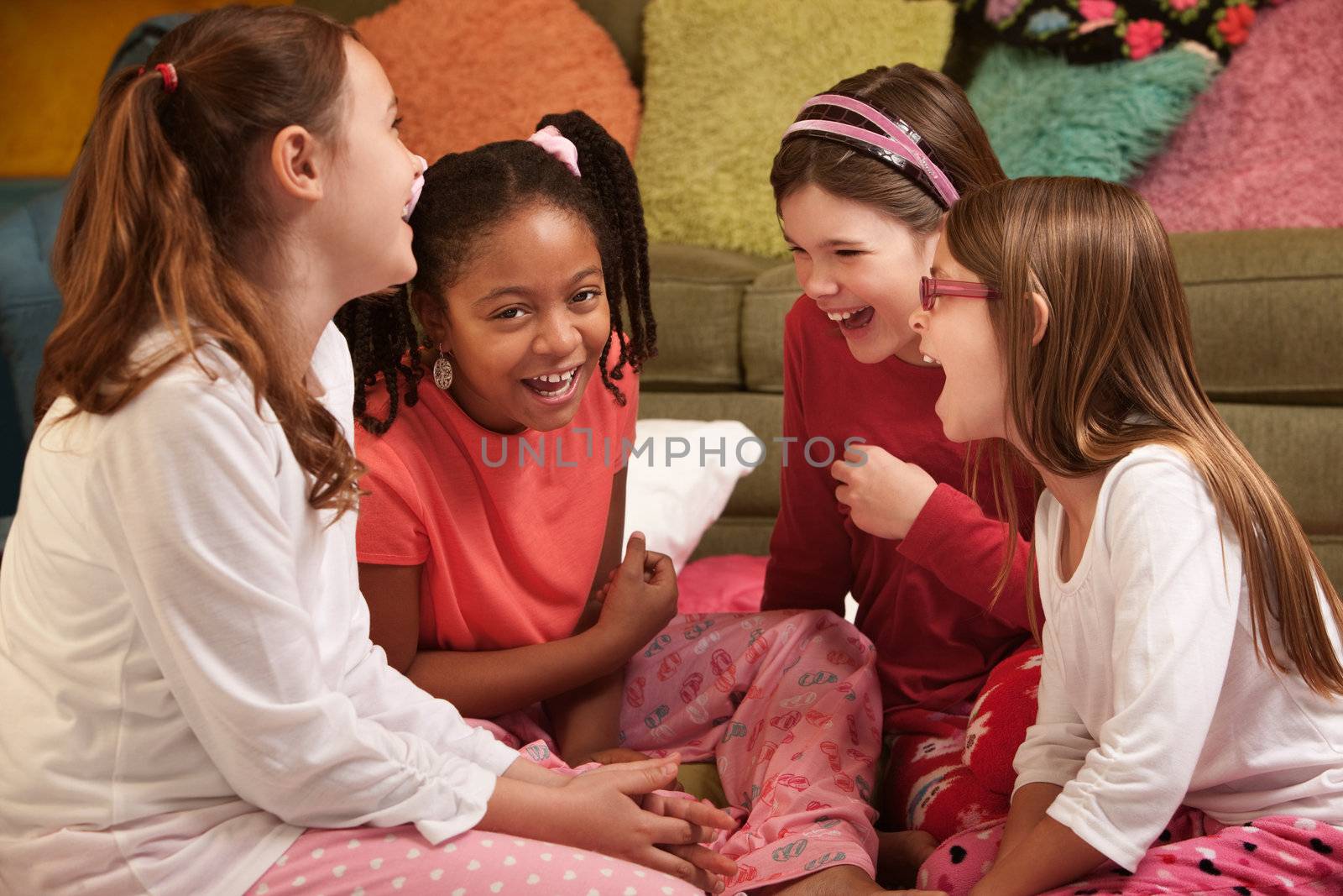 Group of four little girls in pajamas laugh at a sleepover