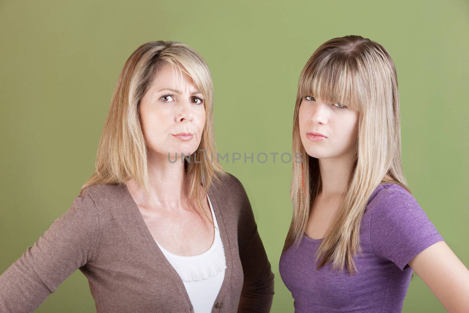 Caucasian mom and daughter over green background frown
