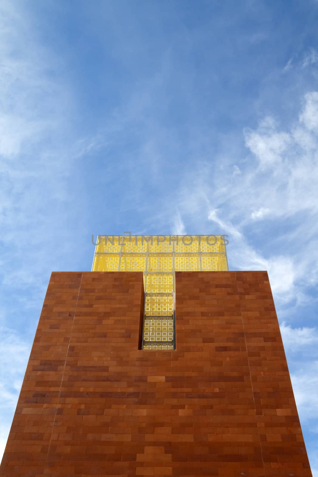 A brick tower with yellow glass at the top