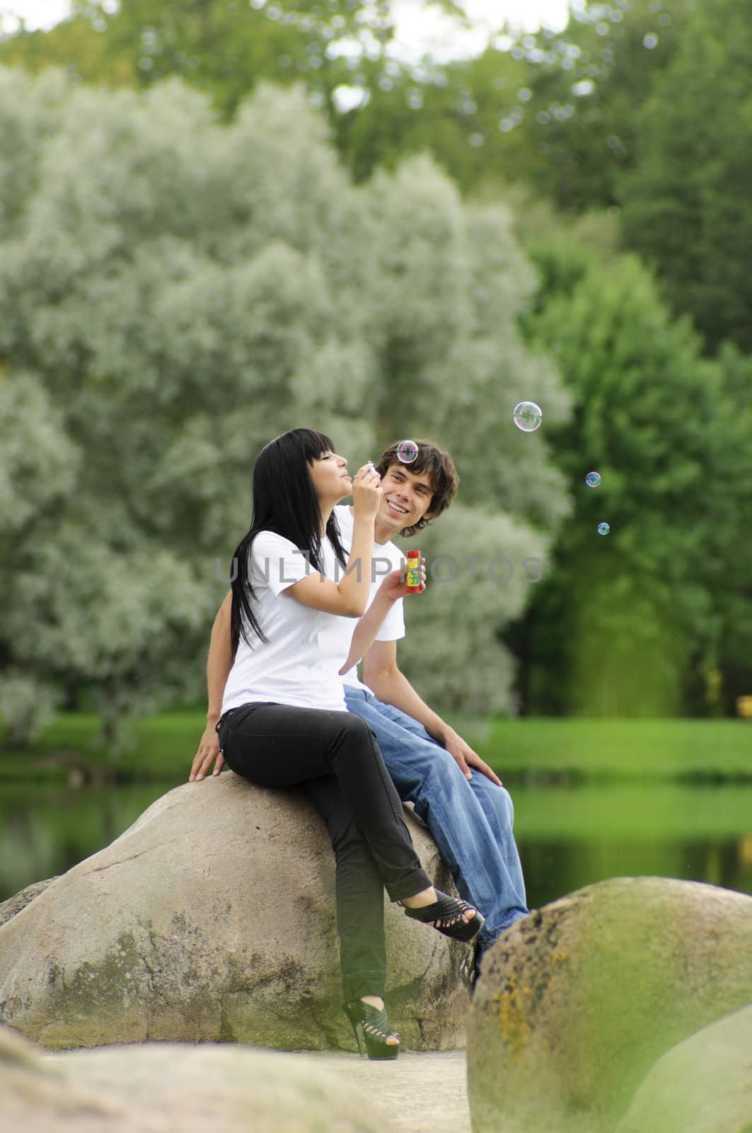 Happy young couple enjoying at park with bubbles