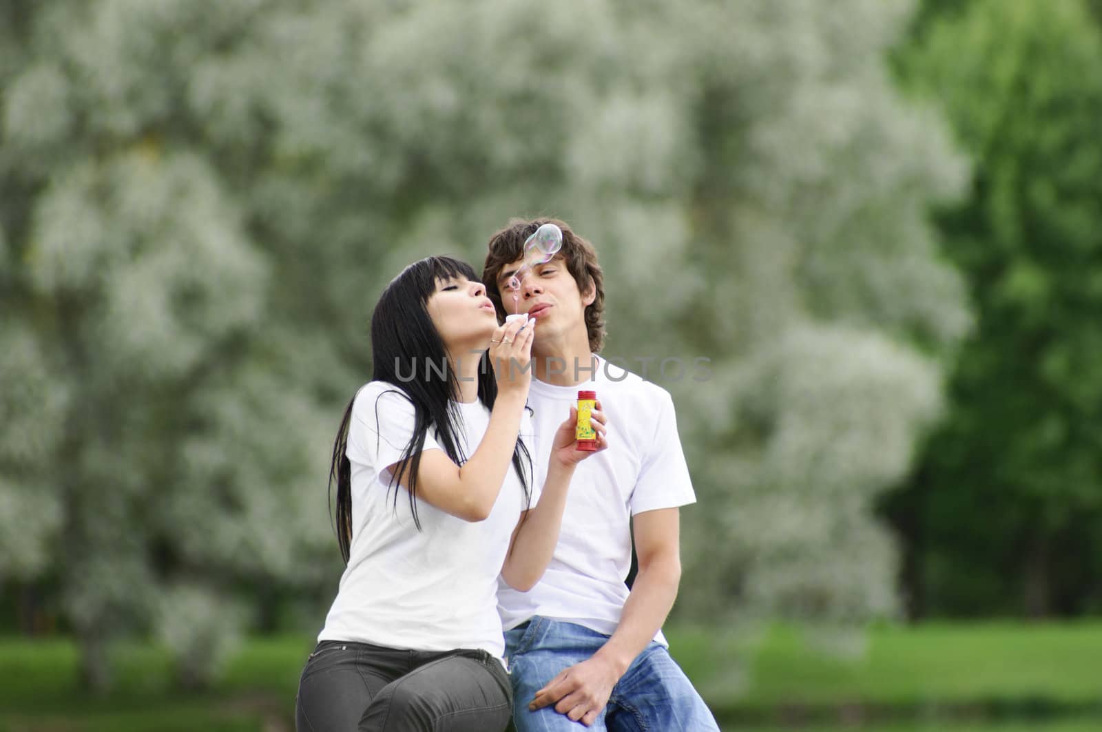 Happy young couple enjoying at park with bubbles