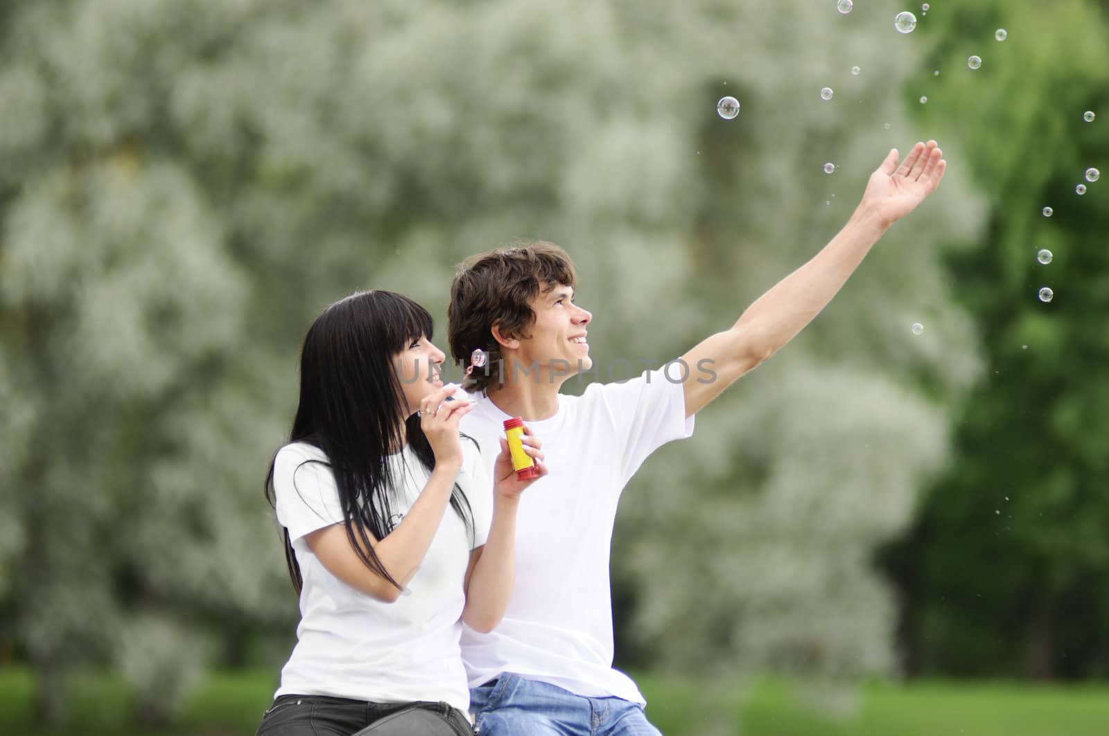 Happy young couple enjoying at park with bubbles