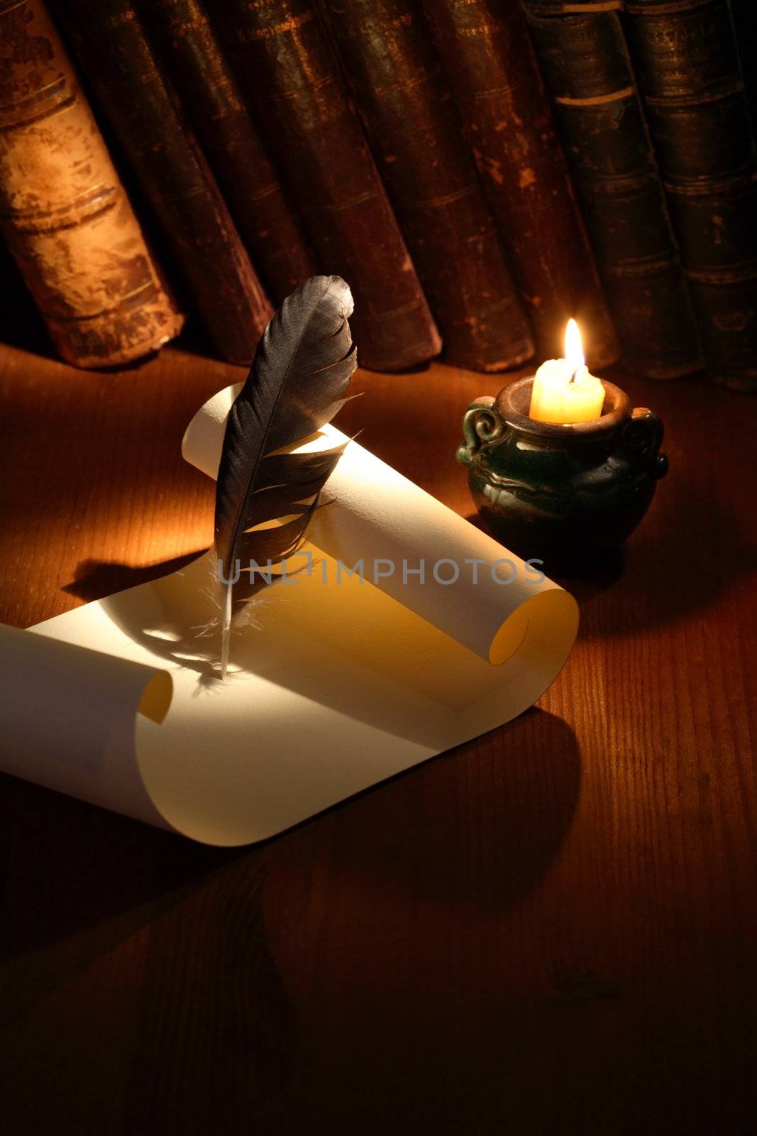 Vintage still life with scroll and quill on wooden surface near lighting candle