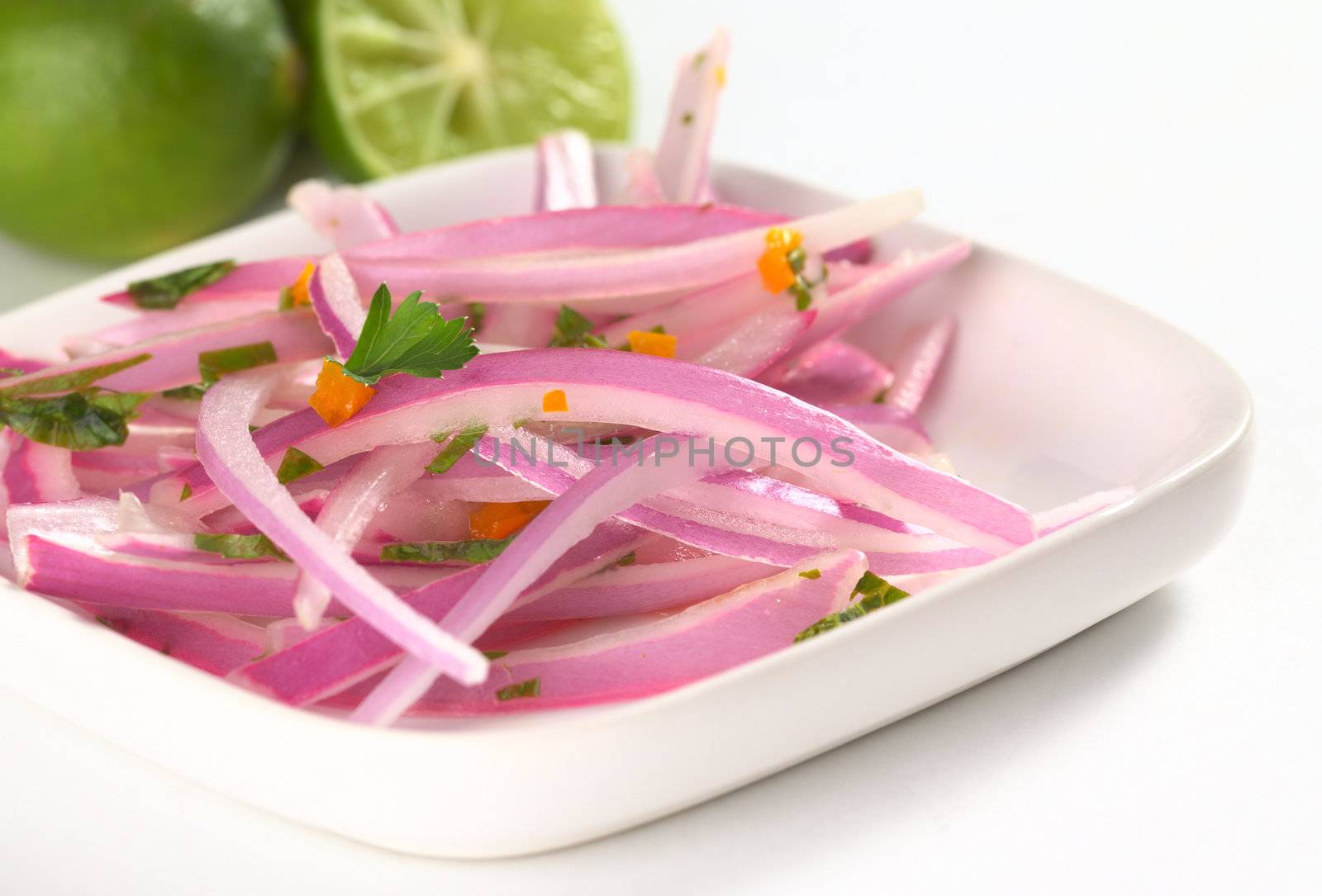 Peruvian Salsa Criolla made of red onion slices, hot pepper called aji, fresh parsley and limes (Very Shallow Depth of Field, Focus on the onion slice in the middle) 