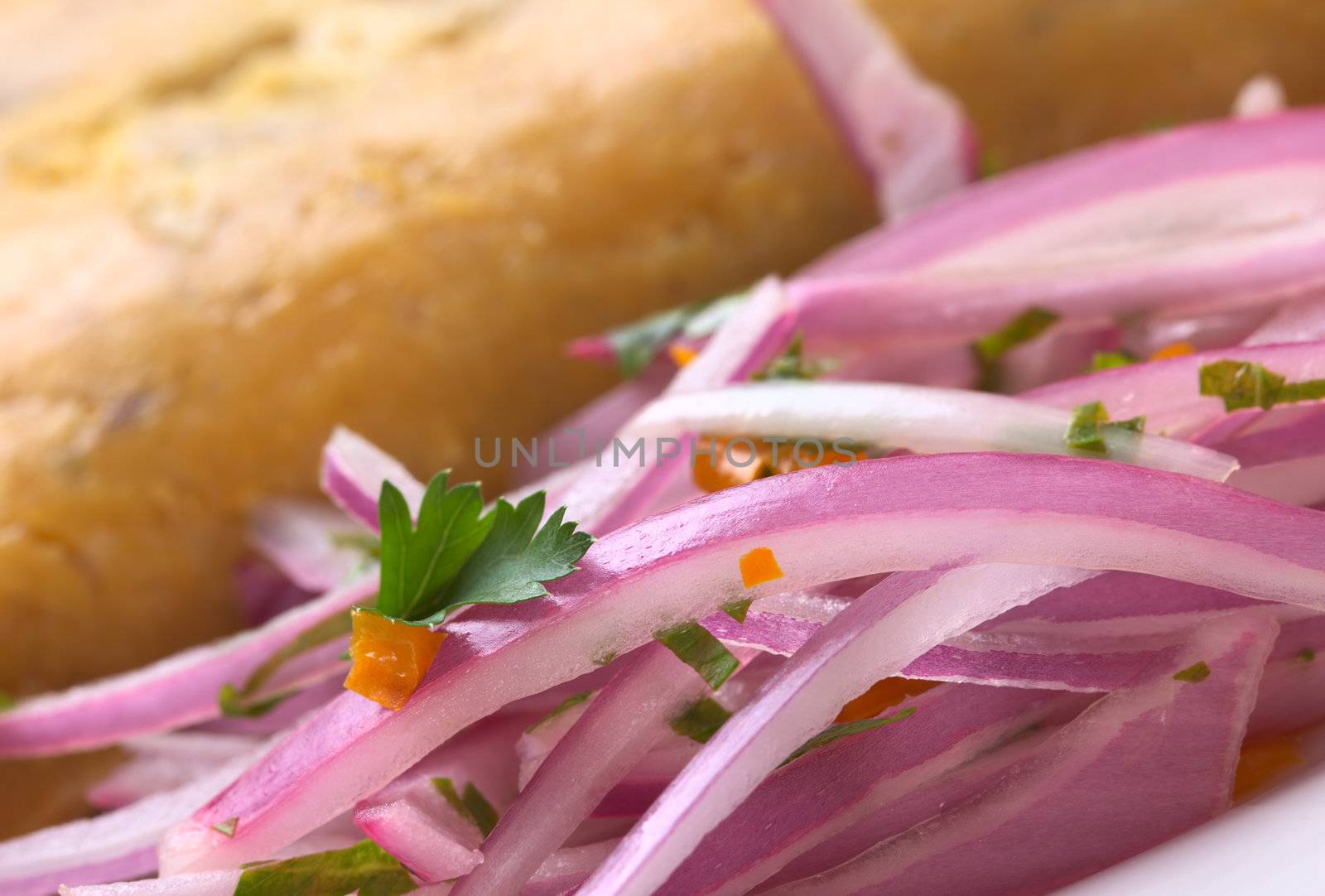 Peruvian Salsa Criolla made of red onion slices, hot pepper called aji, fresh parsley and limes with tamal (cooked corn traditionally eaten for breakfast) (Very Shallow Depth of Field, Focus on the parsley leaf) 