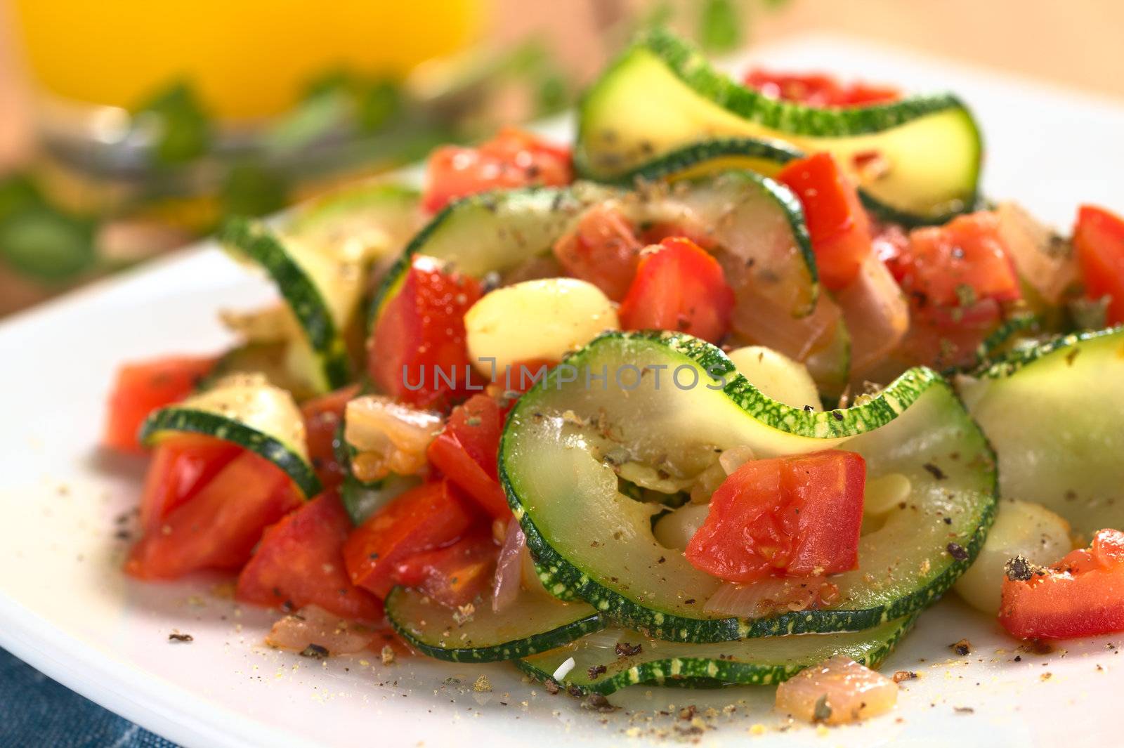 Sauteed zucchini slices, tomato cubes, onion and cooked corn grains with dried herbs and black pepper (Selective Focus, Focus on the front of the zucchini slice and tomato piece in the front)