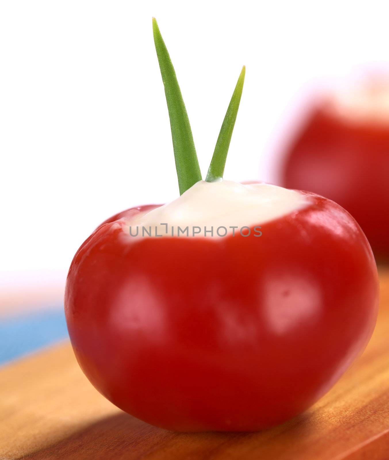Small round hot red pepper filled with sour cream and garnished with chives (Very Shallow Depth of Field, Focus on the chives)