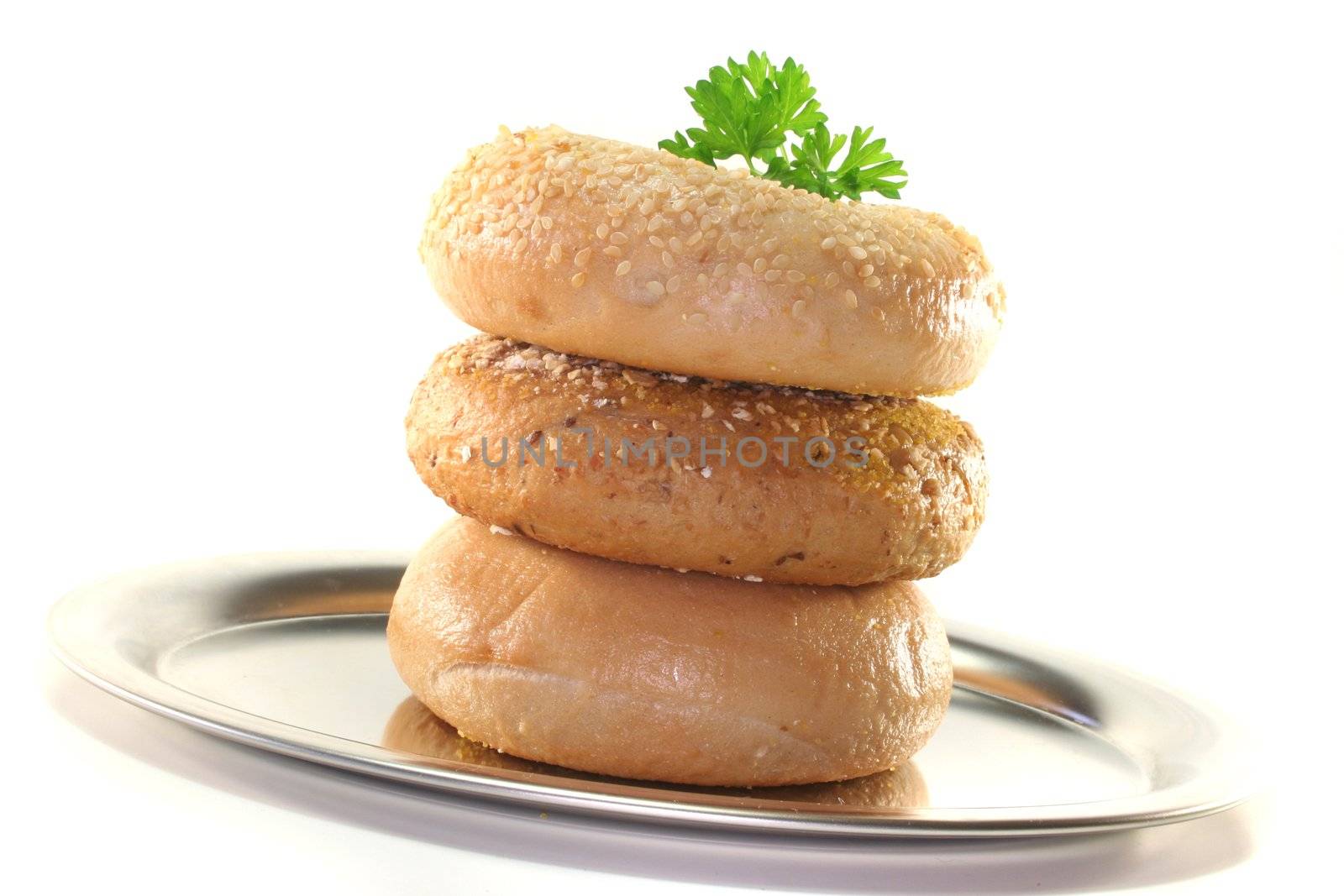 three bagel with parsley on a platter before a white background