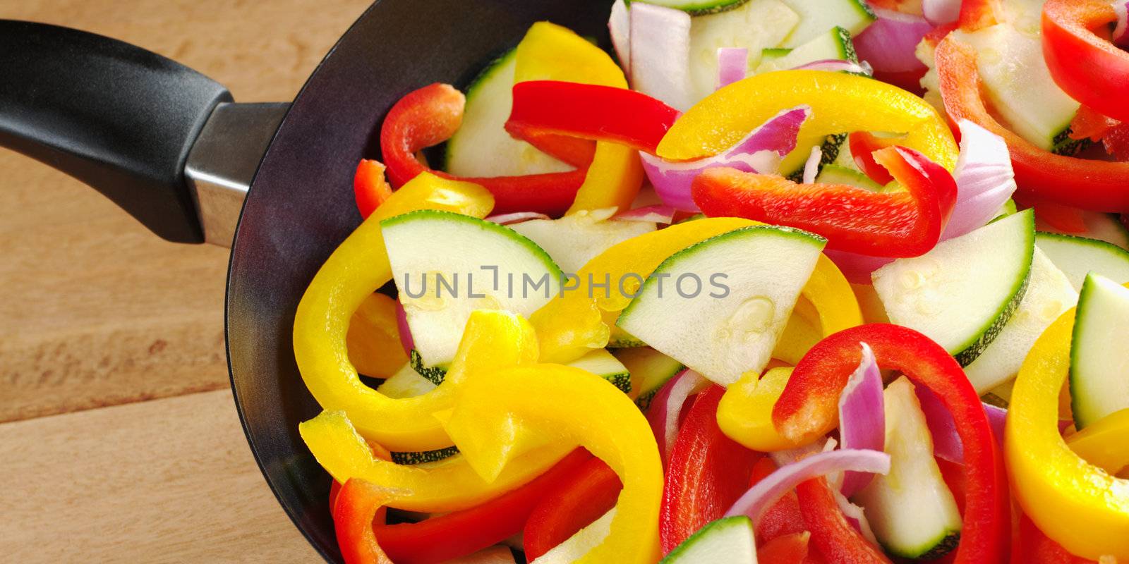 The raw ingredients of ratatouille in a frying pan. Ratatouille is a light summer French dish which mainly consists of zucchini, pepper and onions, but there are many variations to it (Selective Focus, Focus on the upper half of the image)