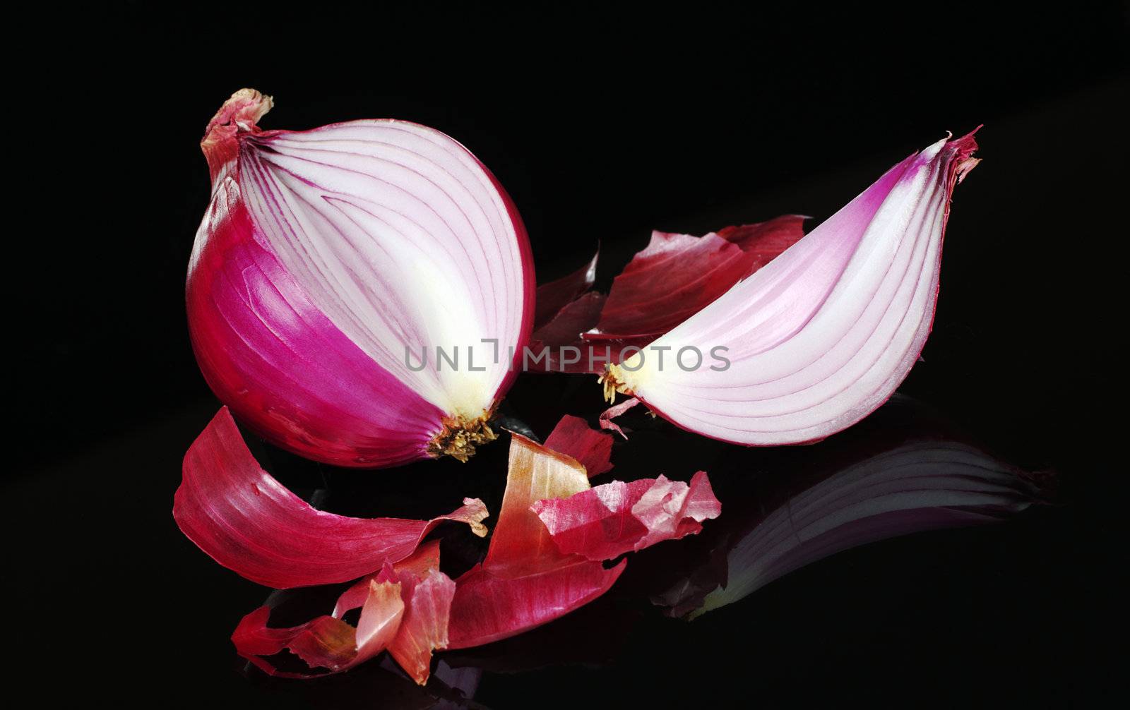 Red onion cut and with peel photographed on black 