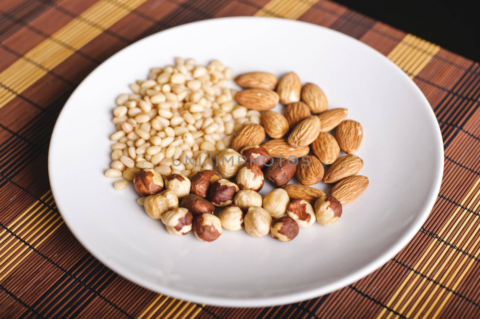 Mixed nuts on a white plate and brown table-napkin