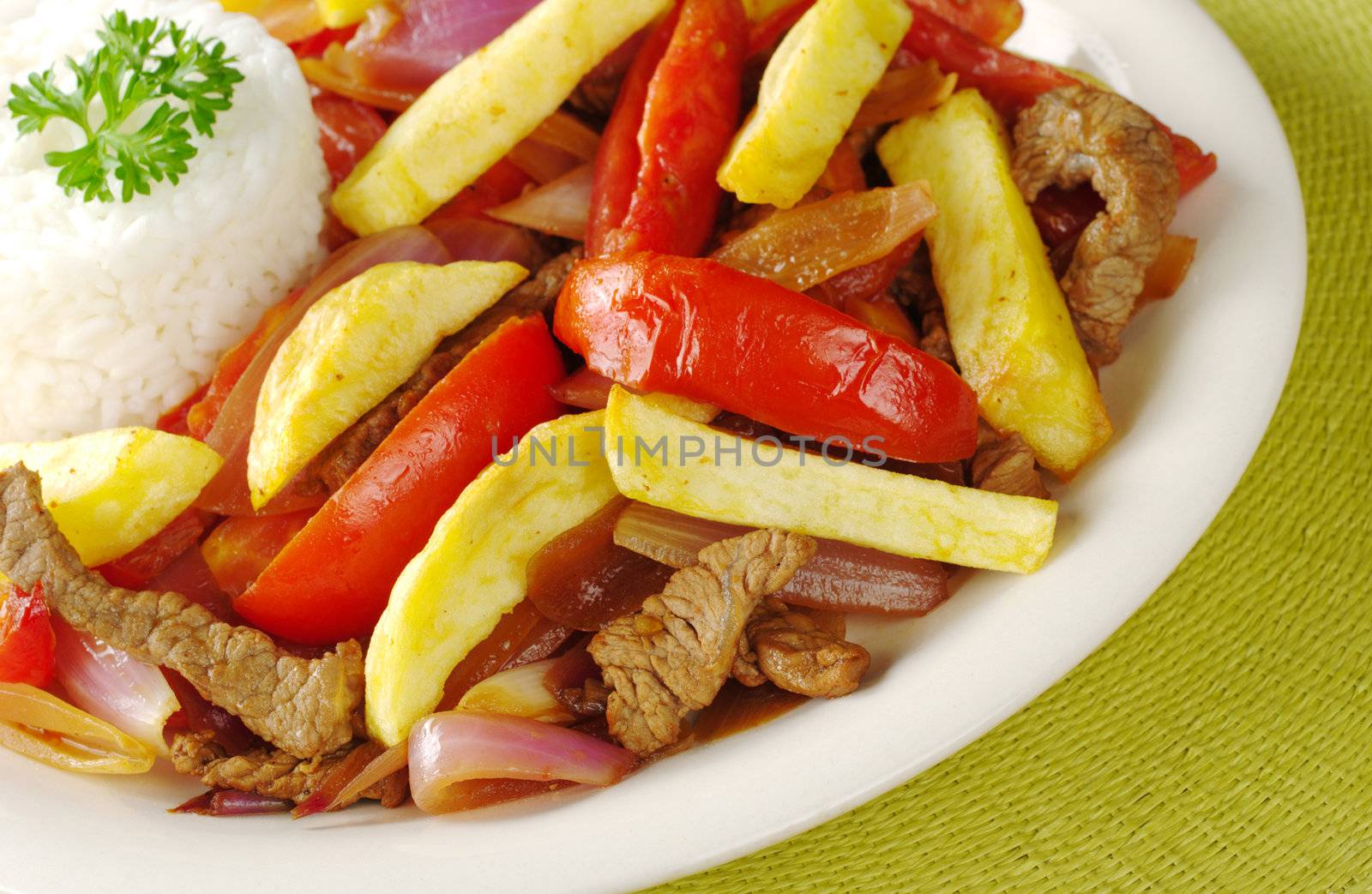 A typical Peruvian dish called Lomo Saltado which is made of beef, onions, tomatoes and is accompanied by fried potatoes and rice (Selective Focus, Focus on the front of the dish)