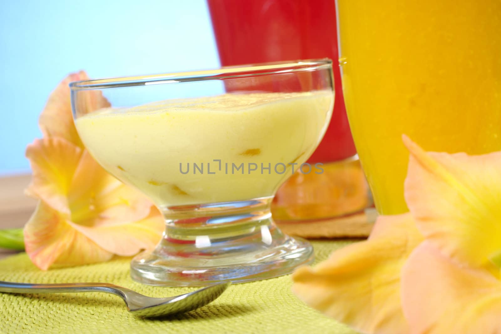 Light summer cream-cheese-mango dessert with mango and watermelon smoothies and gladiolus flowers (Selective Focus, Focus on the front of the dessert)