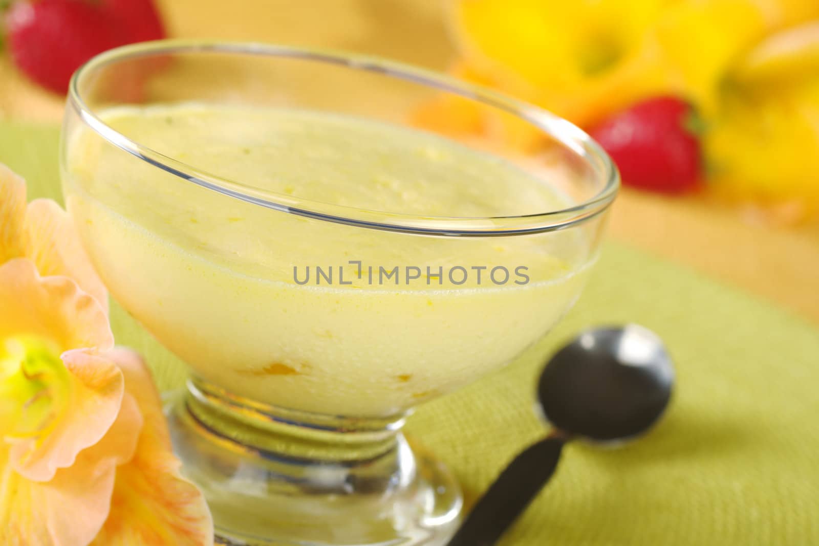 Cream cheese dessert with spoon, gladiolus and strawberries (Selective Focus, Focus on the front of the bowl)