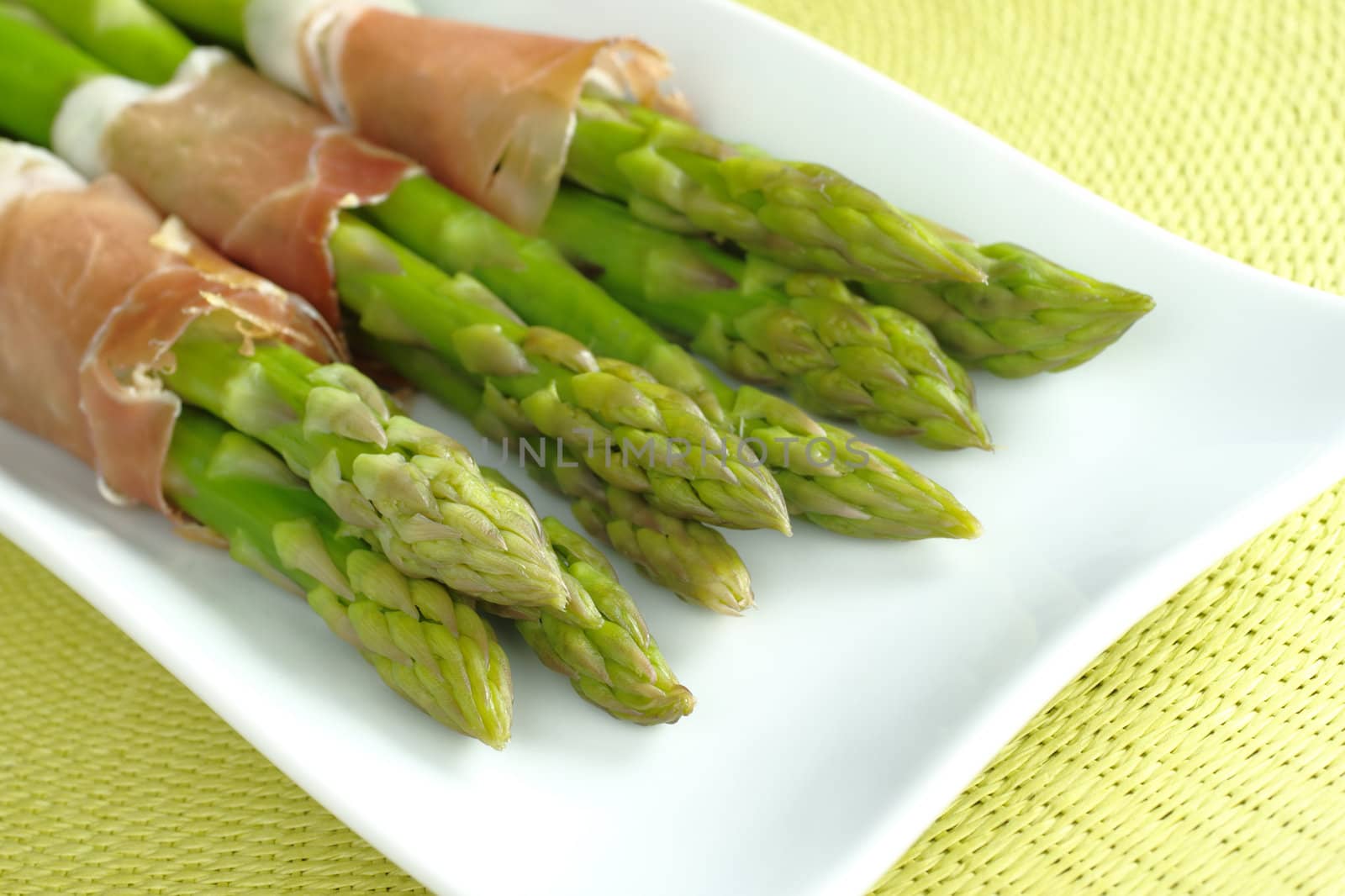 Green asparagus with ham (Selective Focus, Focus on the asparagus heads in the front)