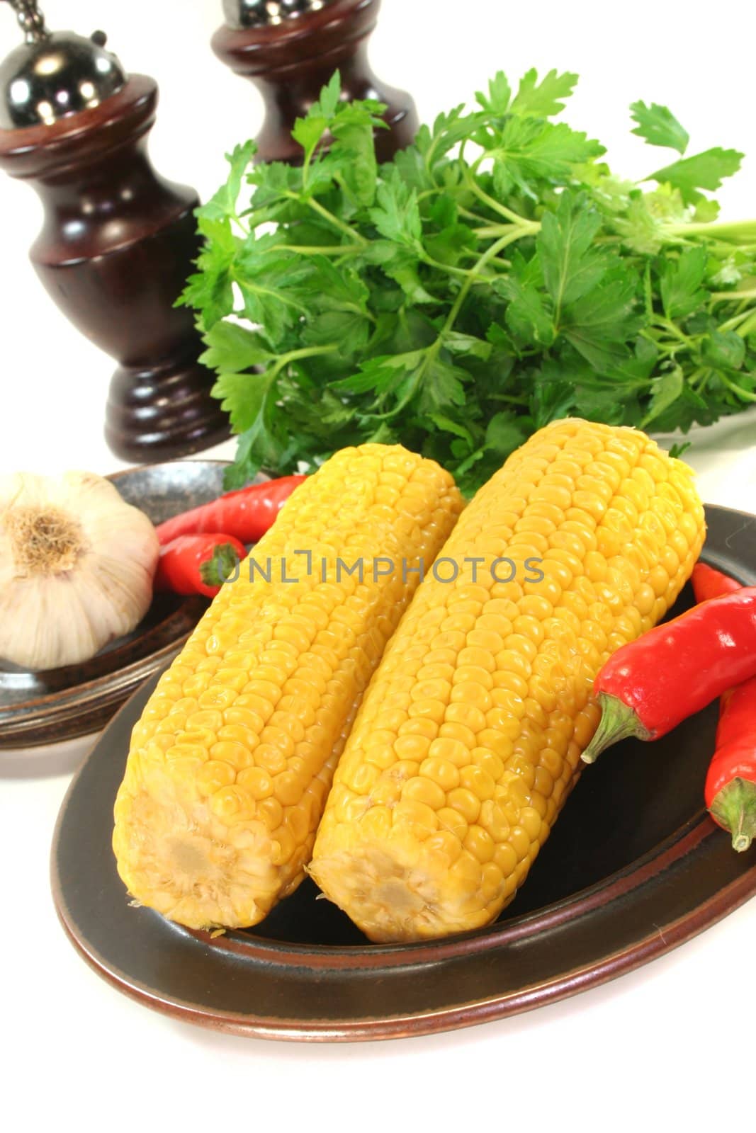 Corn on a plate with chili peppers, garlic and parsley