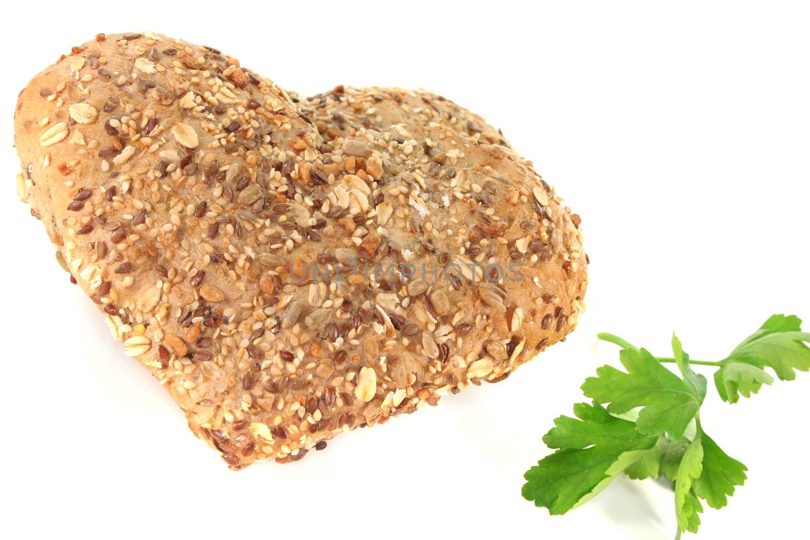 Whole grain bread into heart shape with parsley on a white background