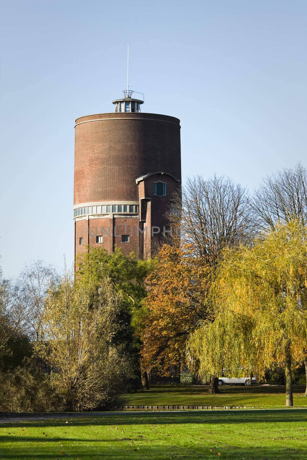 Park with old water tower in fall with colorful trees and blue sky