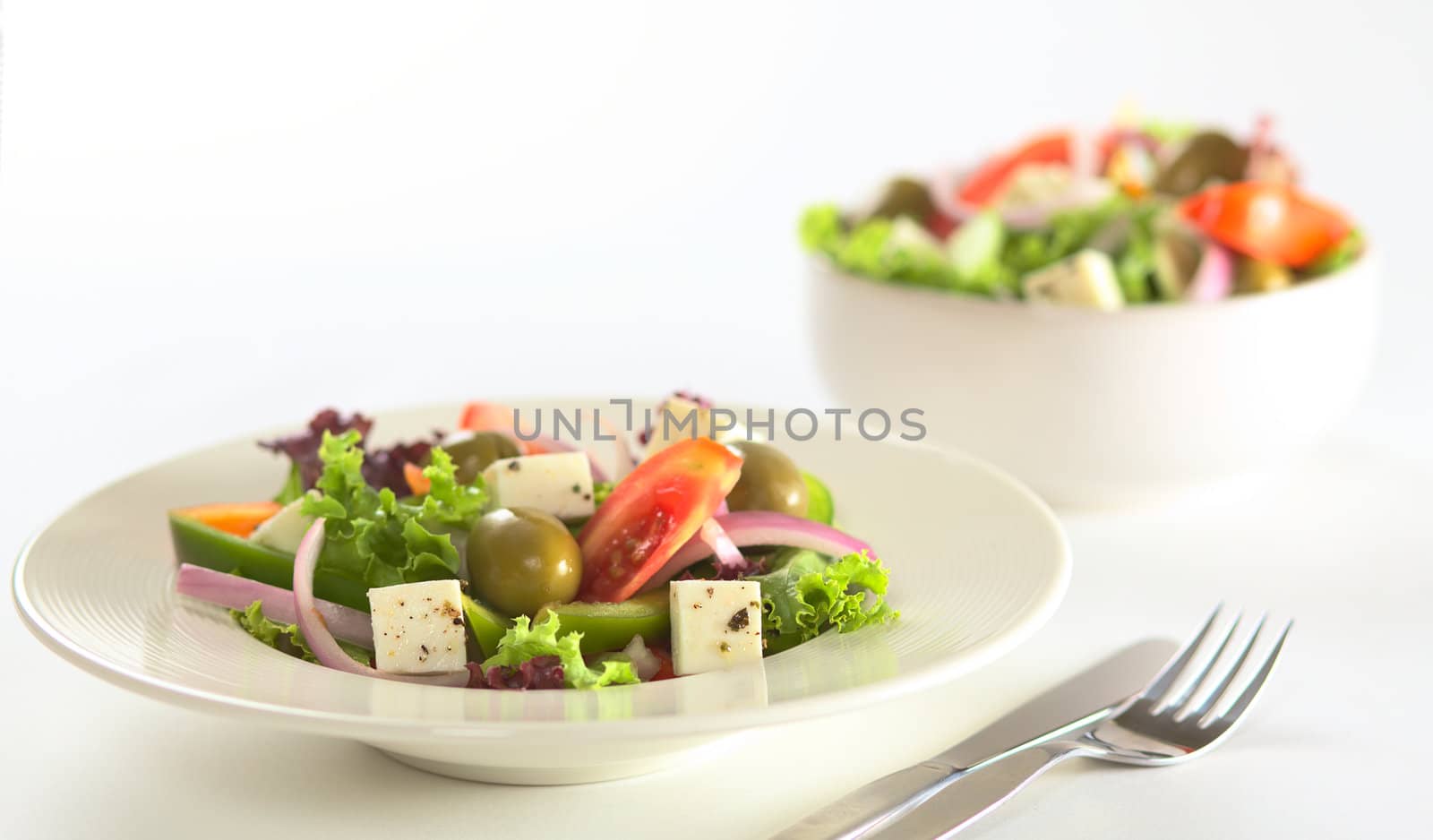 Greek salad out of white cheese, olives, red onions, tomato, bell pepper, cucumber and lettuce with herbs (Selective Focus, Focus on the front of the salad) 