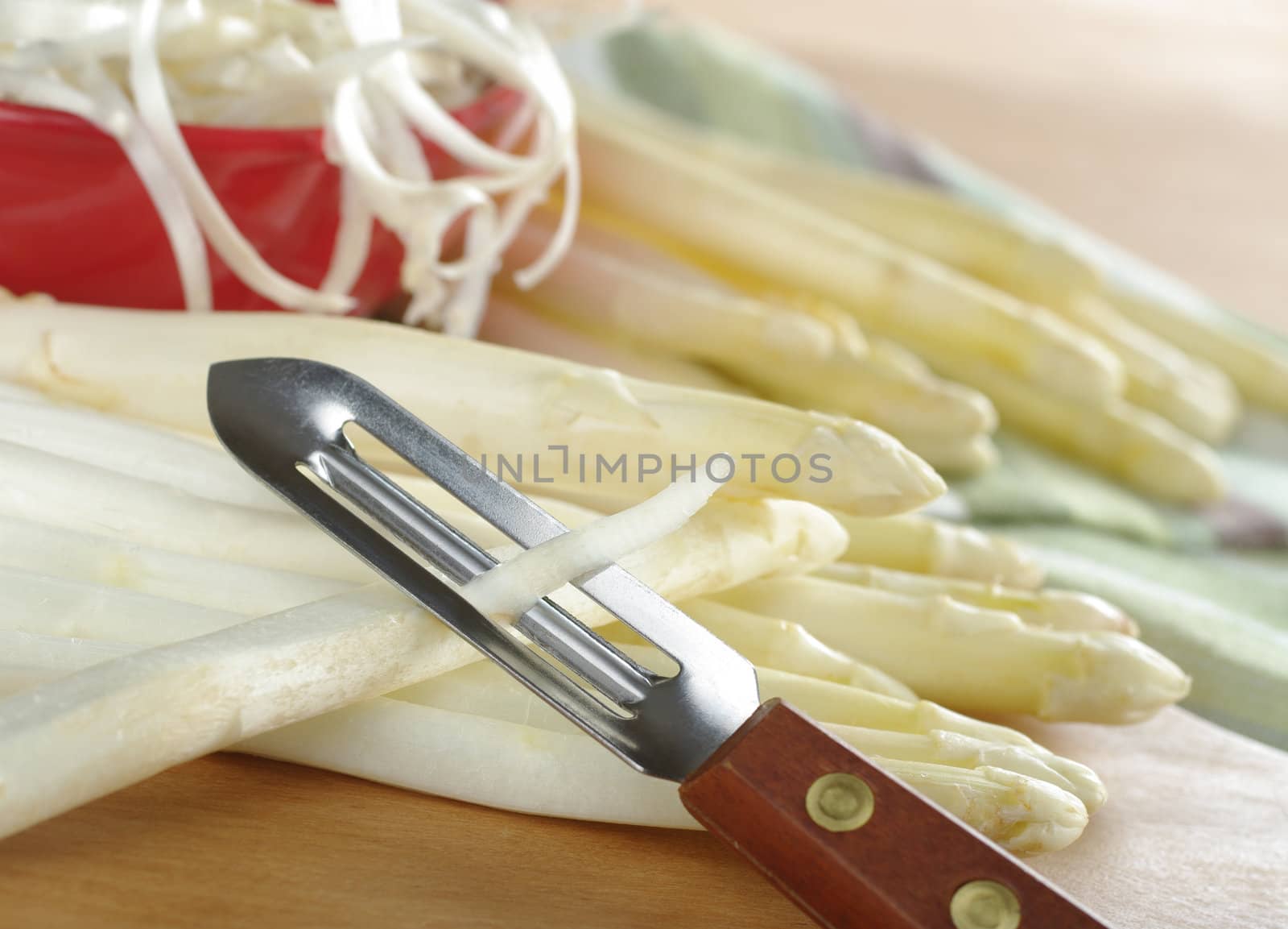 Peeling white asparagus (Selective Focus, Focus on the blade of the peeler and the peel) 