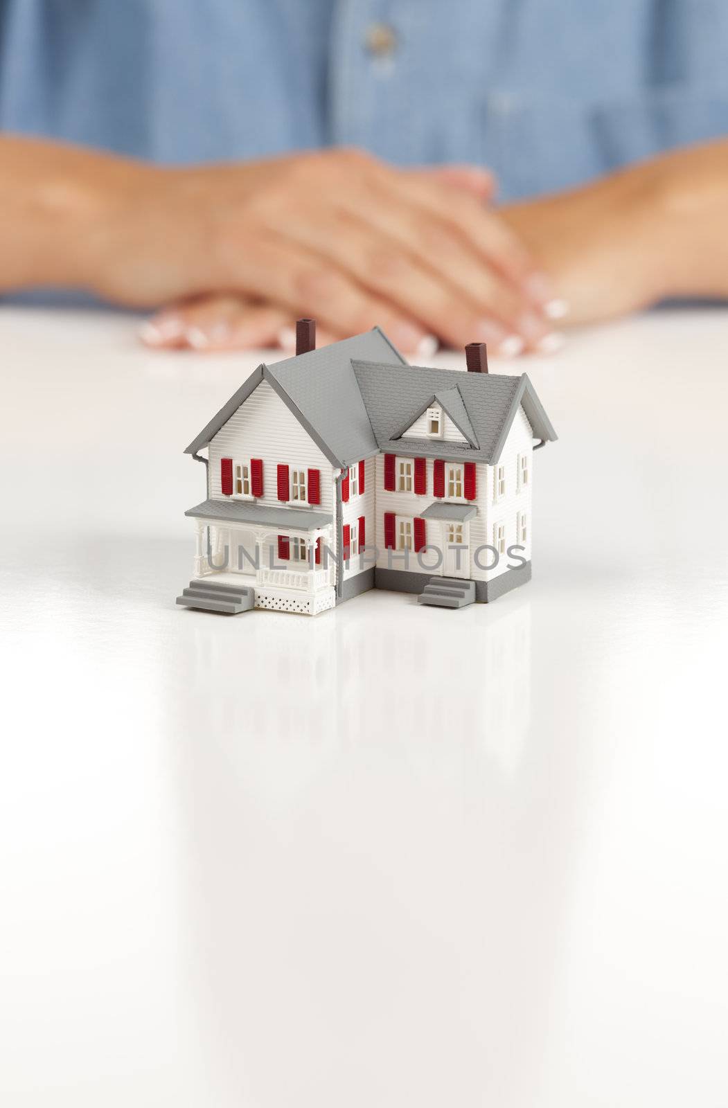 Womans Folded Hands Behind Model House on White Surface.