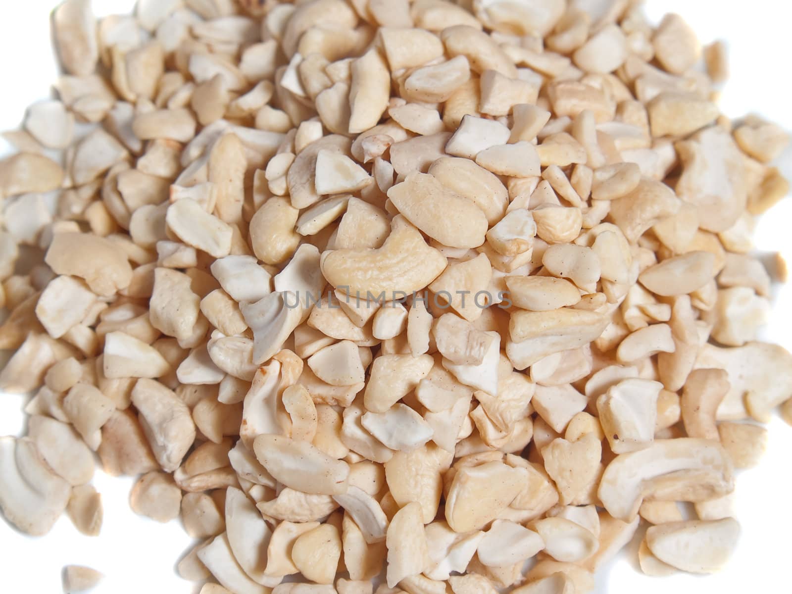 A lot of small pieces cashew nuts on white background
