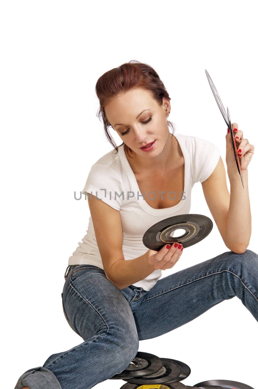 Attractive young woman looking through her vintage records for a rock and roll song to play.