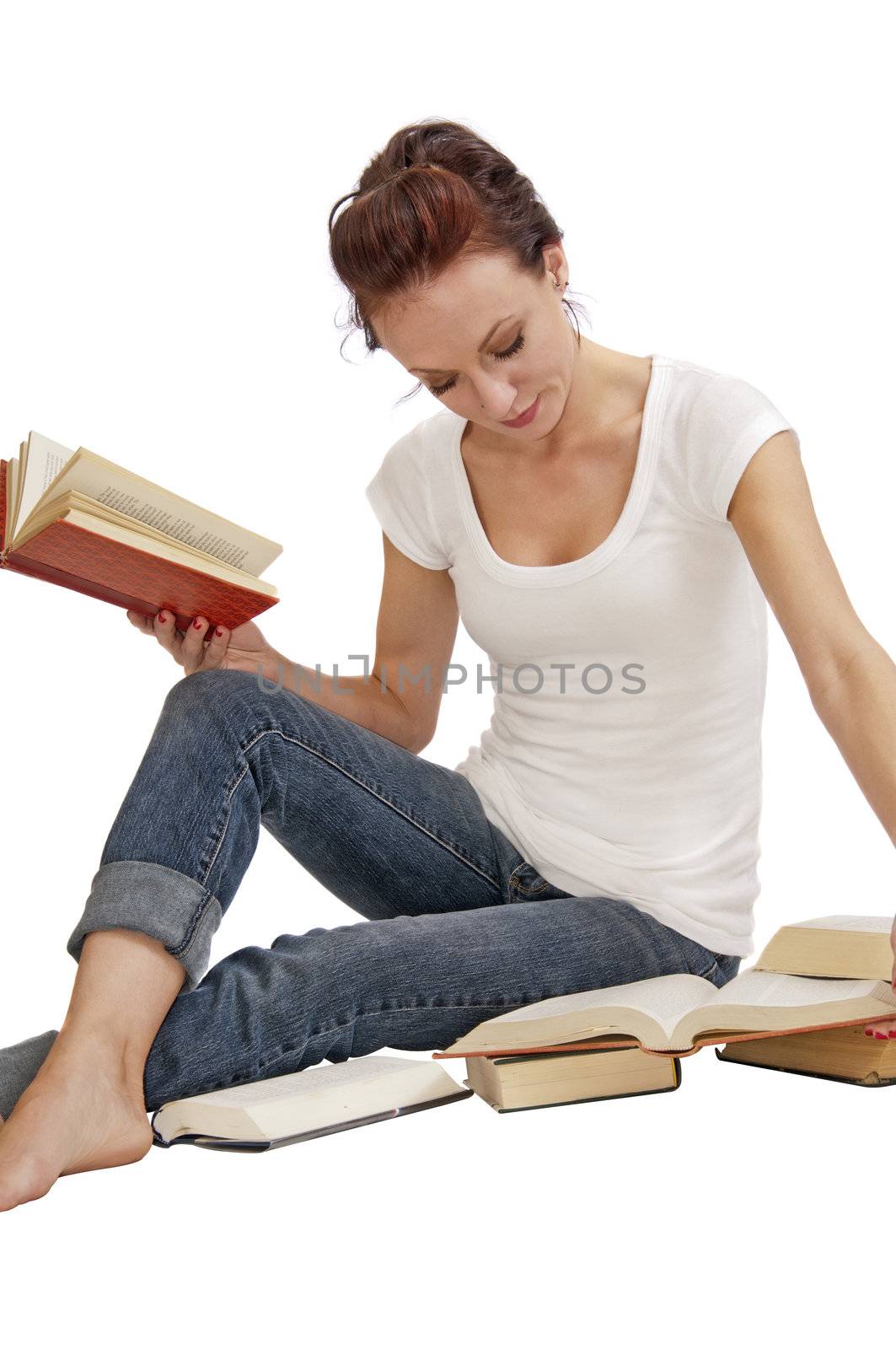 Attractive young woman seated on the floor doing research in old books.