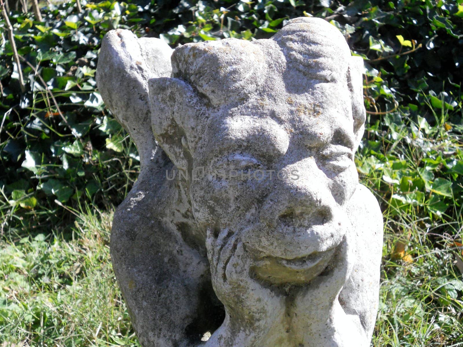 A gargoyle garden statue in autumn sunshine.