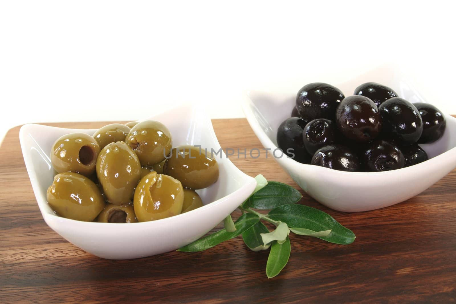 black and green olives with olive branch on a wooden board