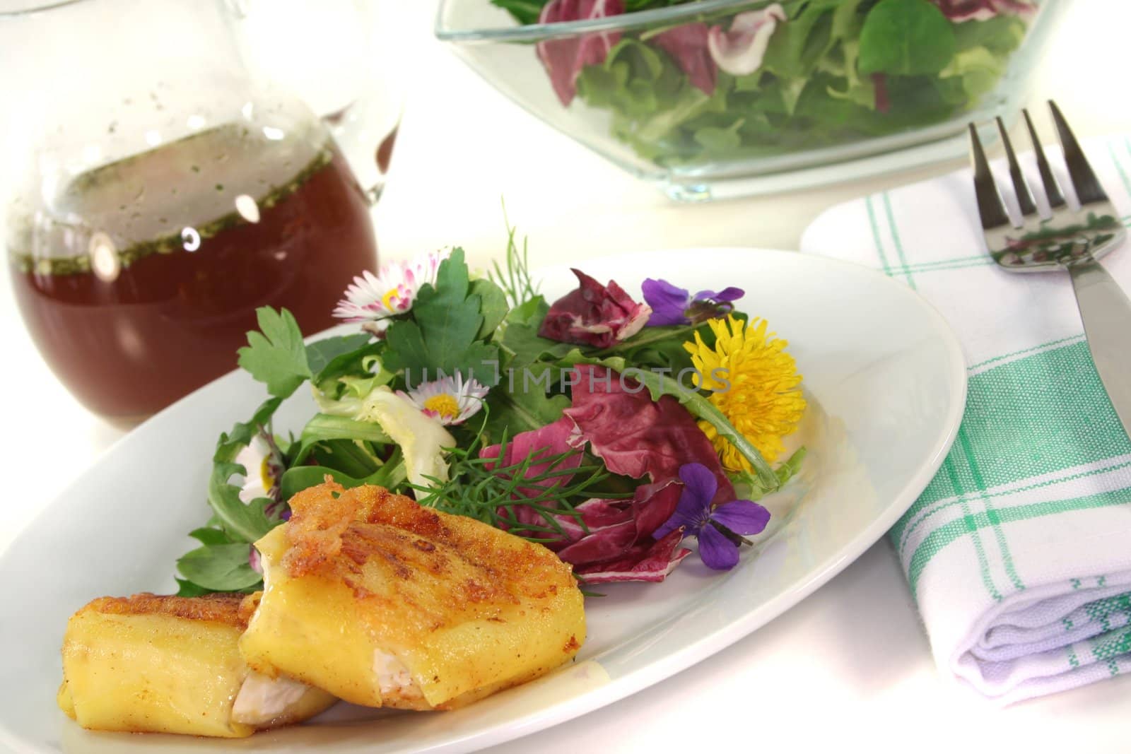 Wild herb salad with goat cheese wrapped in potato on a white background