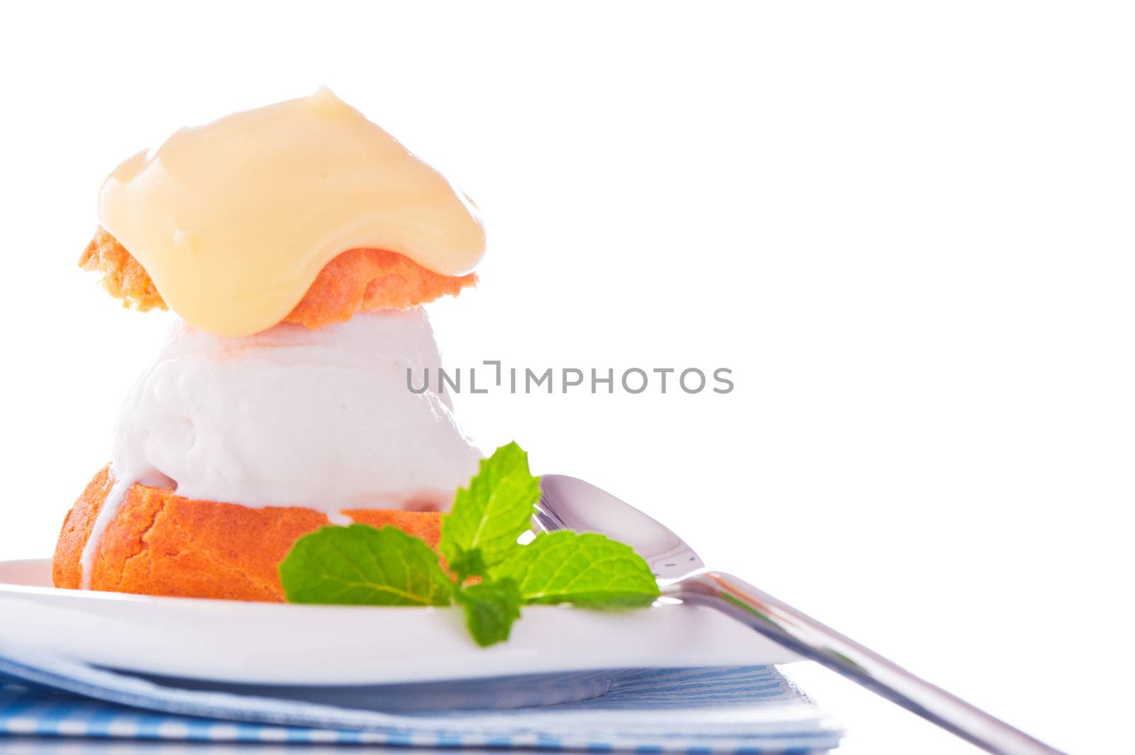 Profiterole in a small plate with ice cream vanilla sauce and mint leaf on a white backgound