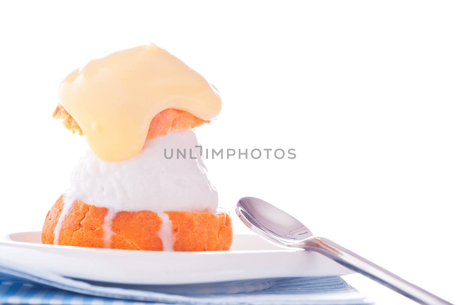 Profiterole in a small plate with ice cream vanilla sauce on a white backgound