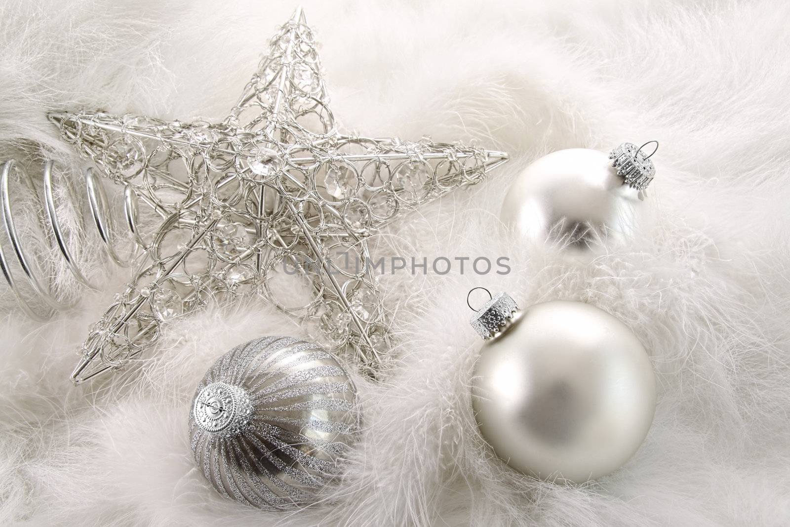 Silver holiday ornaments laying in white feathers