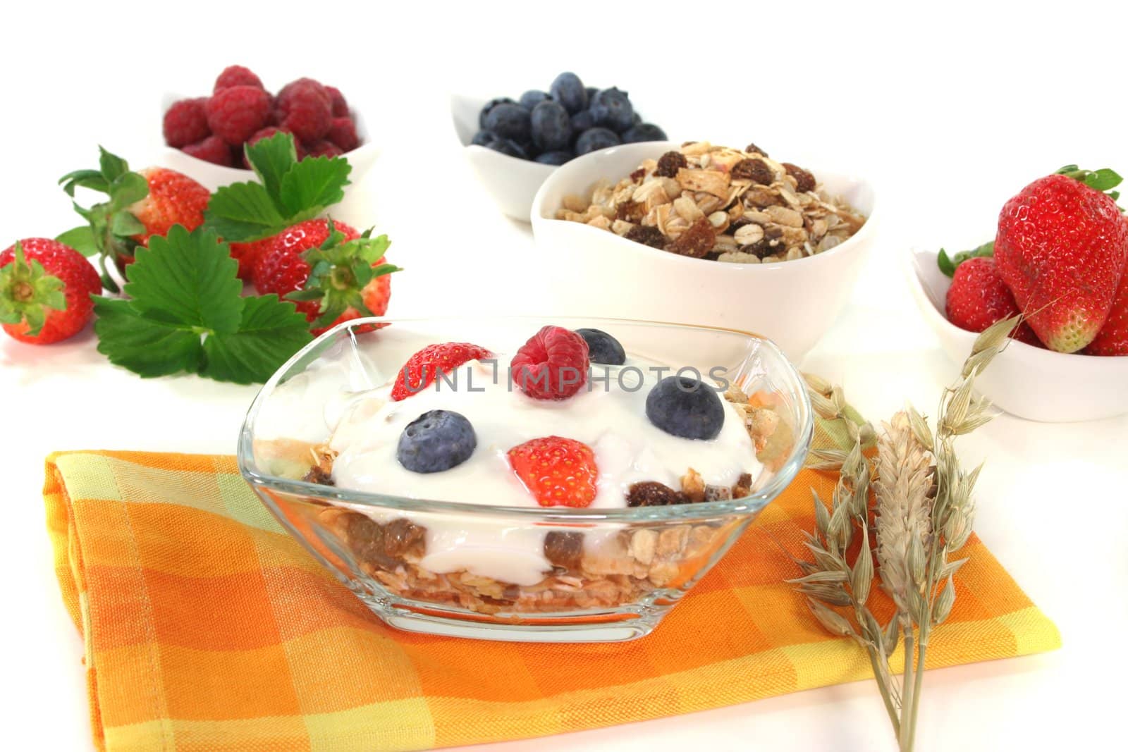 Cereal bowl with yogurt, fresh fruit, nuts and milk in front of white background