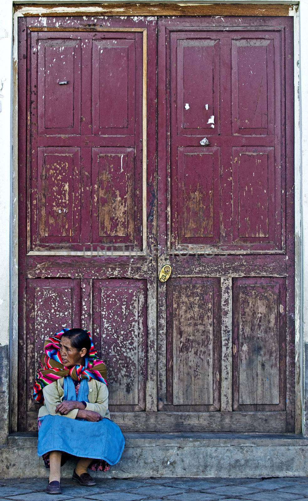 Cusco , Peru - May 30 2011 :  Peruvian woman seat near a door in a street in Cusco Peru 