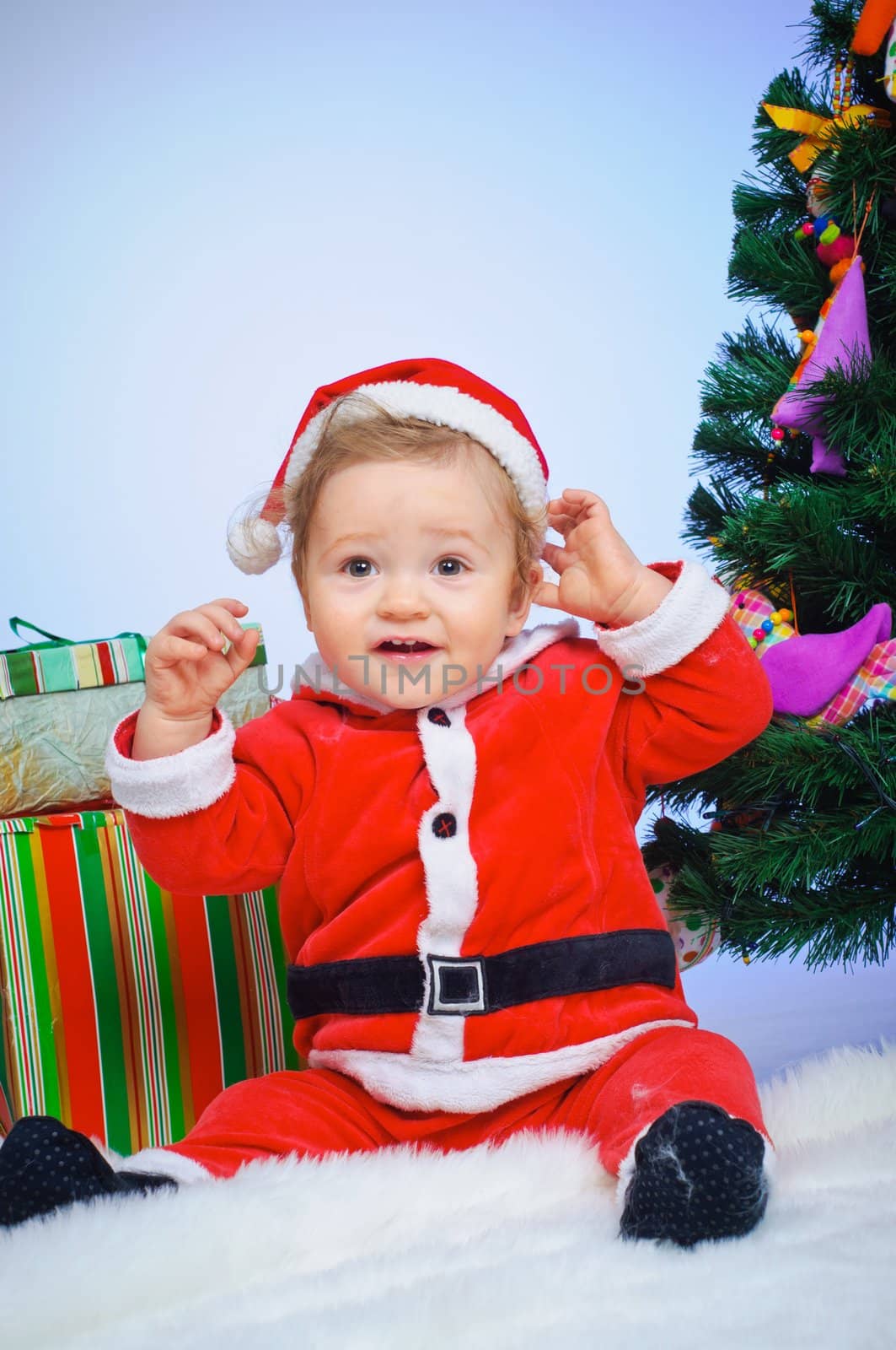 Christmas theme: little Santa - Surprised baby boy with gifts. Vertical view