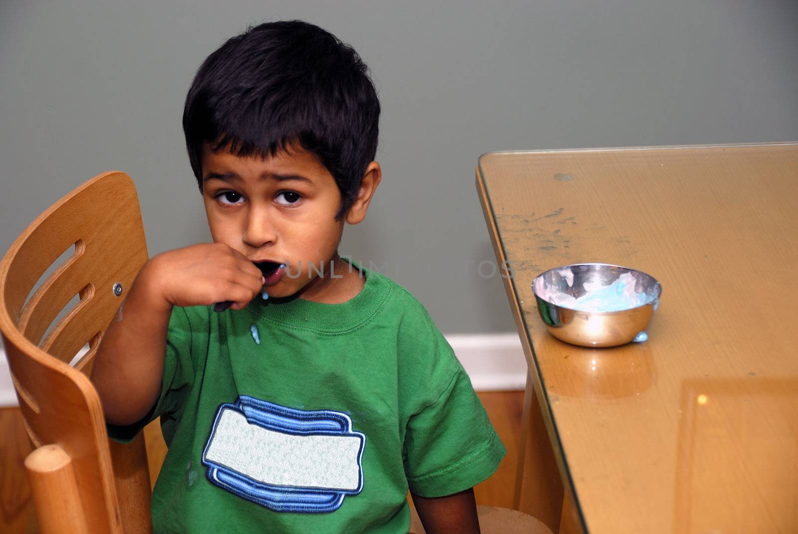 An handsome indian kid enjoying his yoghurt