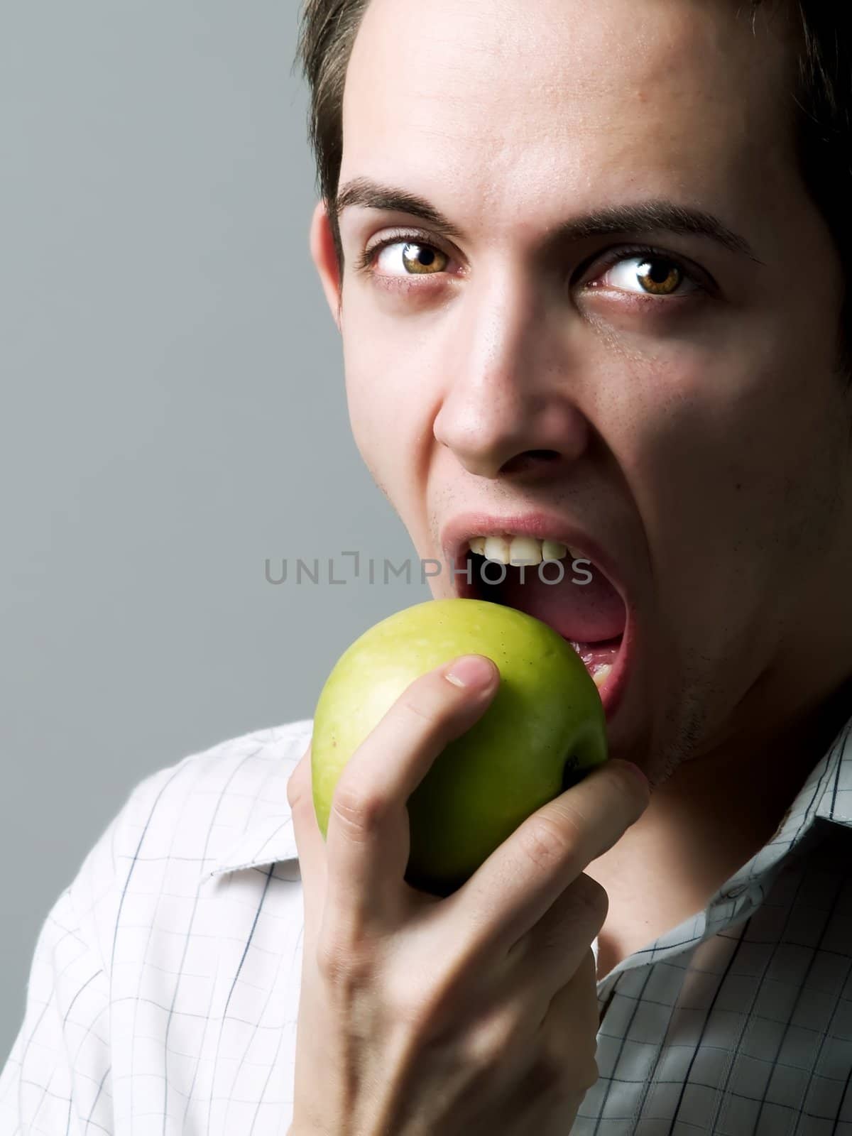 Young man eating a green apple