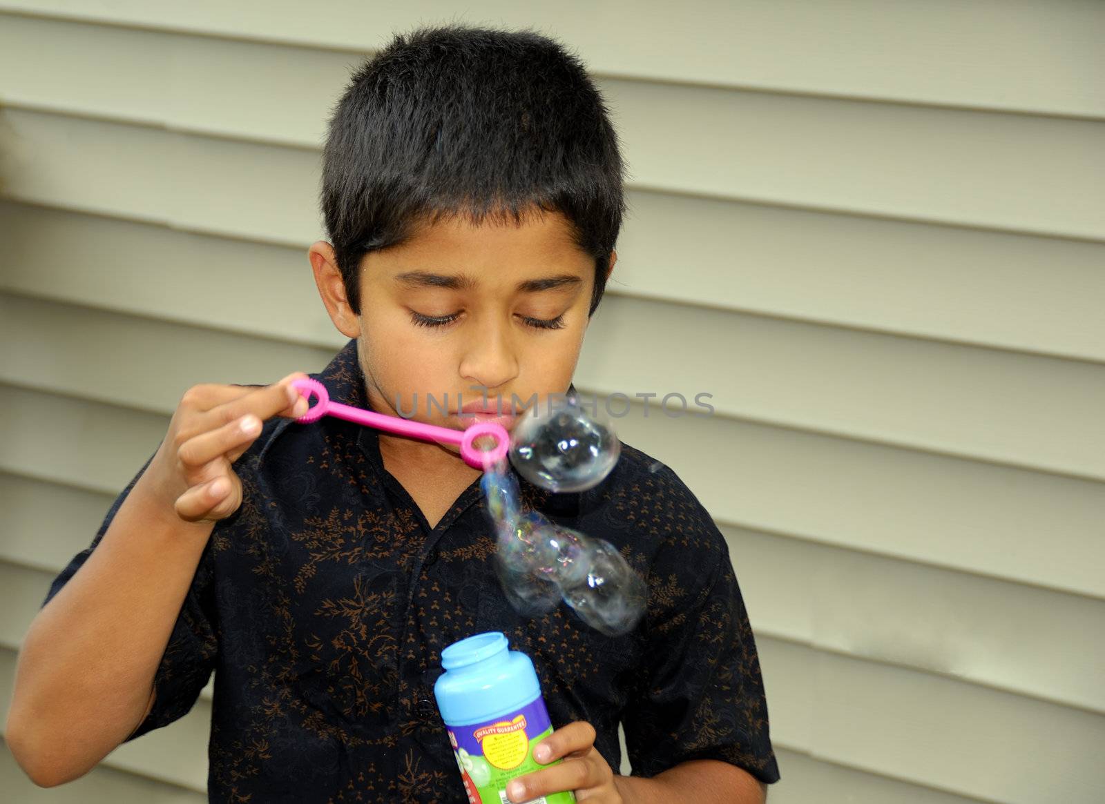 An handsome Indian kid blowing bubbles
