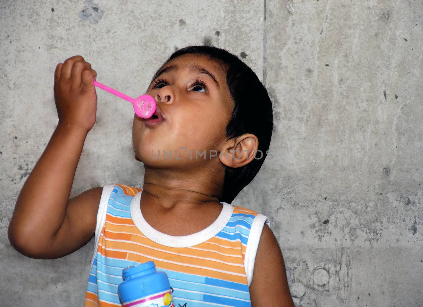 Young Indian kid having fun blowing bubbles