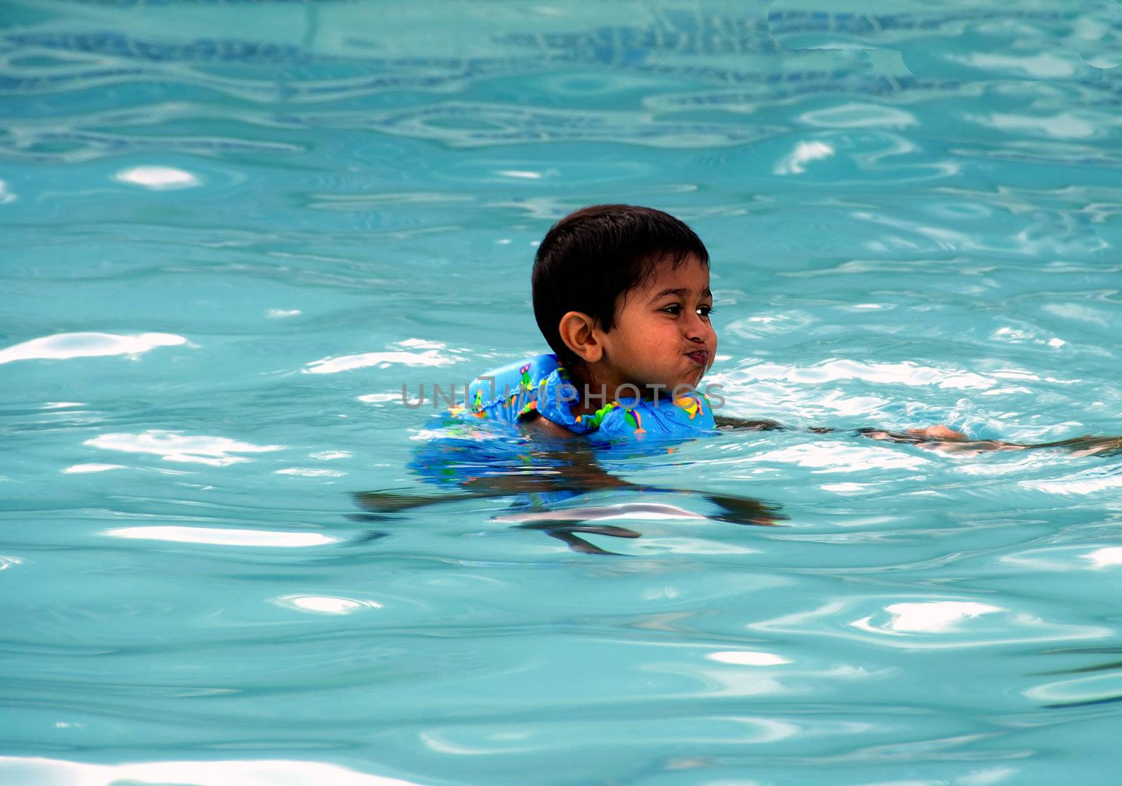 An young indian boy having fun smimming in the pool