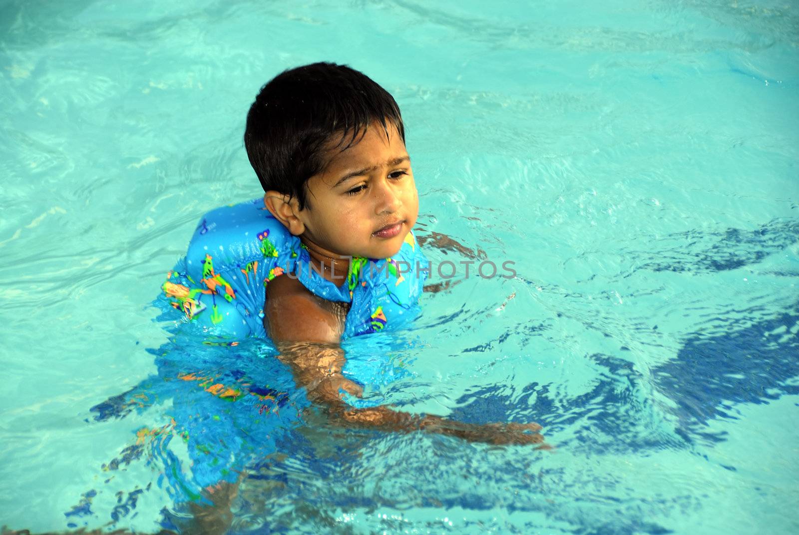 An young indian boy having fun smimming in the pool