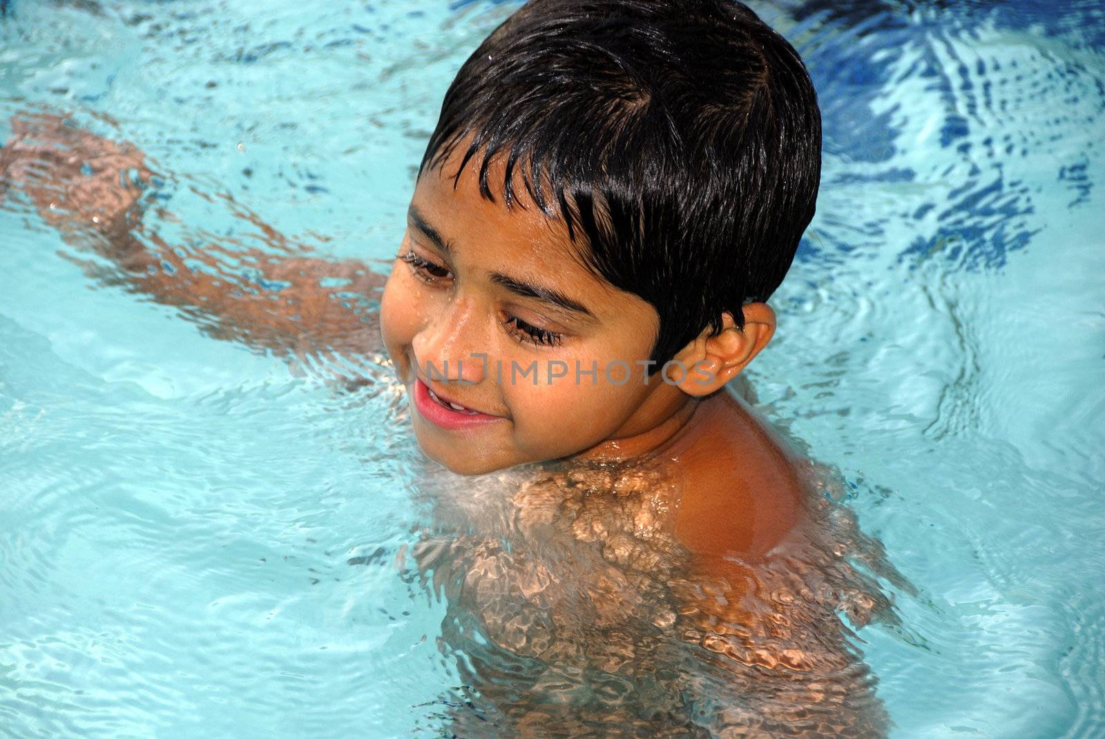 An young indian boy having fun smimming in the pool