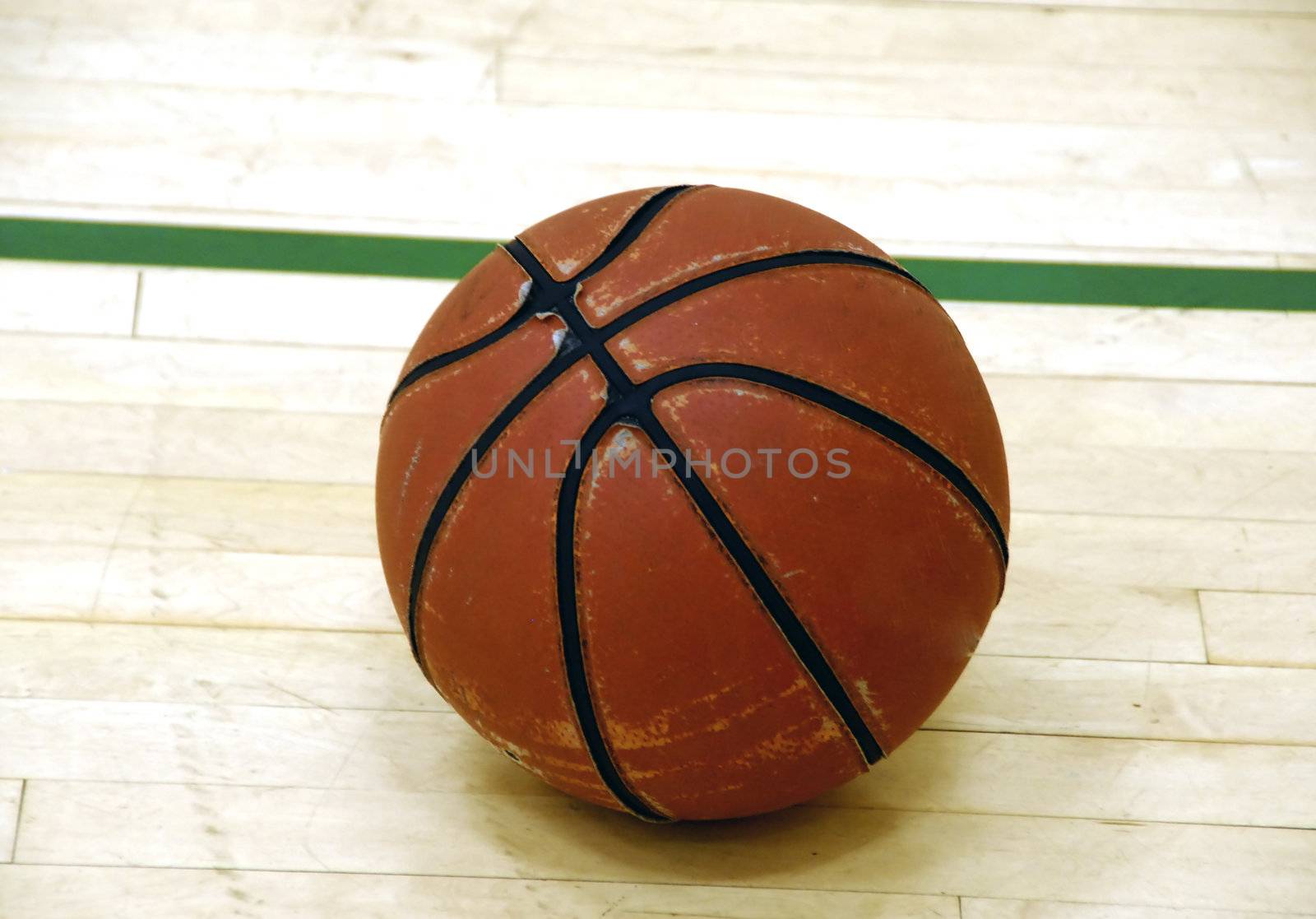 An old basketball on  an indoor wooden court