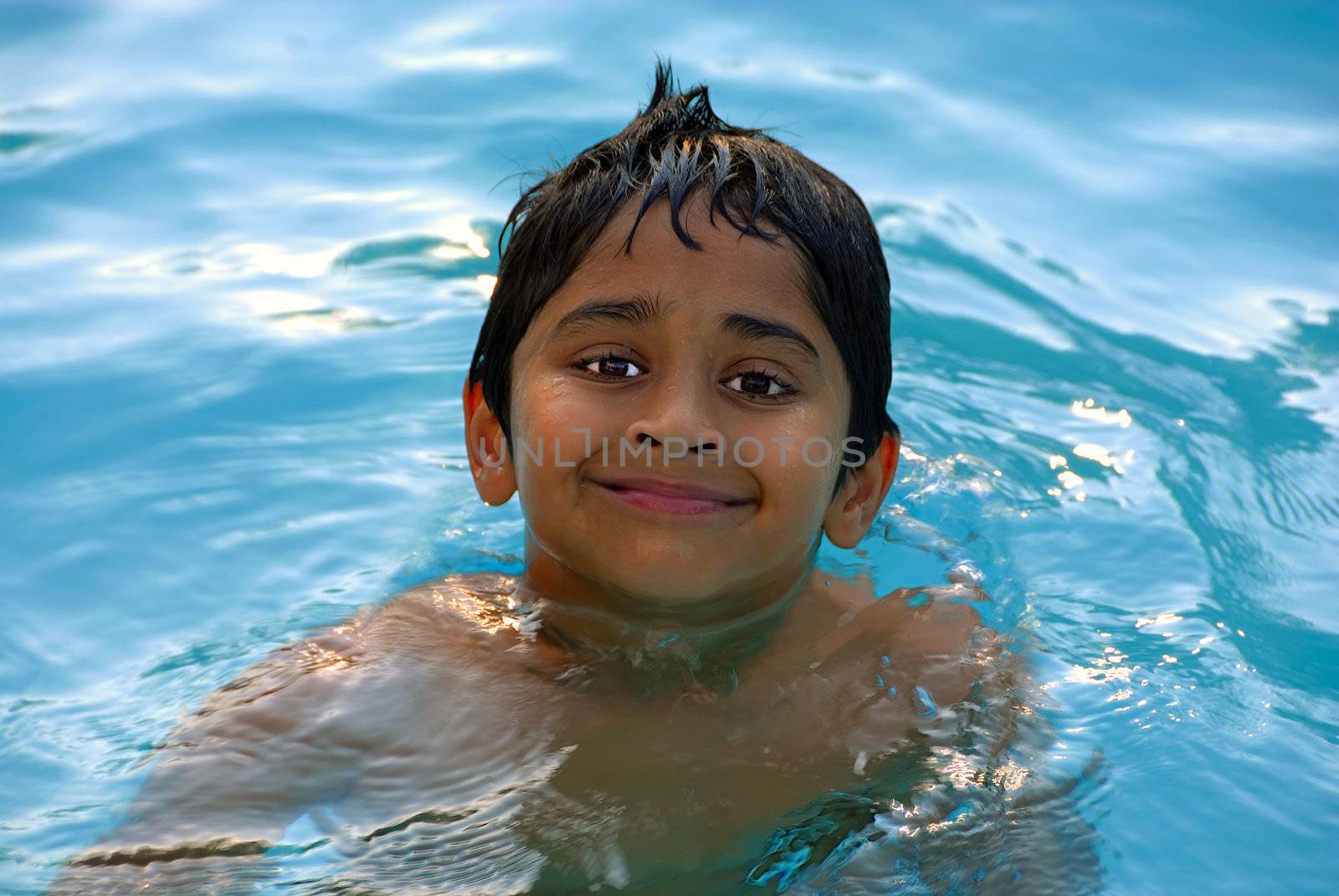 An young indian boy having fun swimming in the pool

