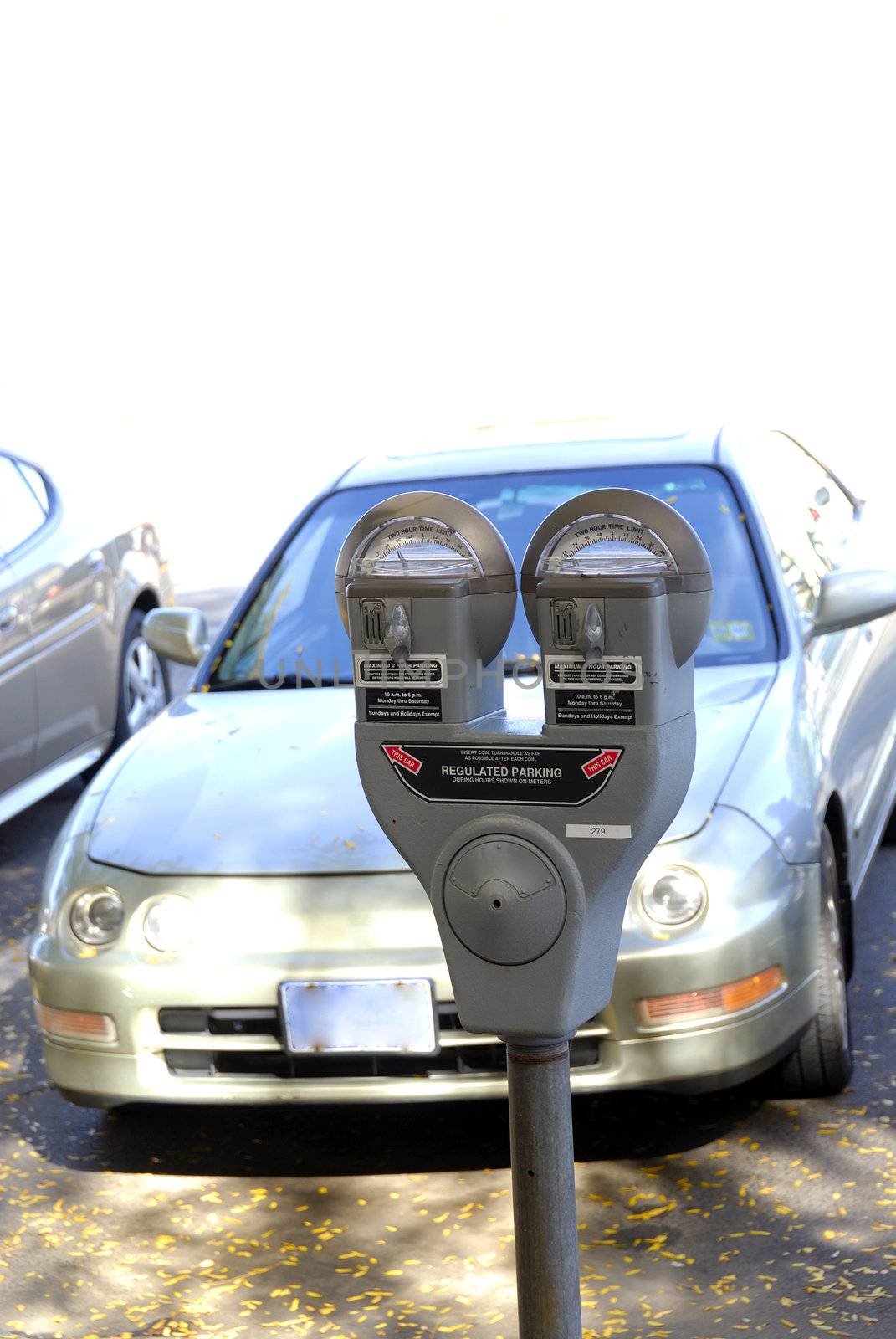 PArking meters againt a shallow depth of cars parked at the background