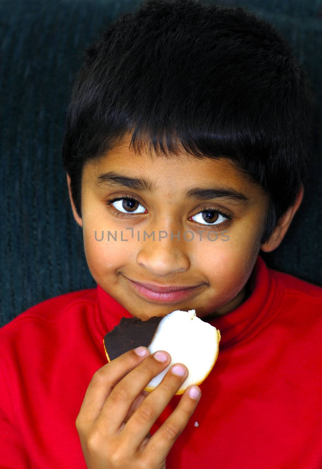 An handsome indian kid enjoying his cookie